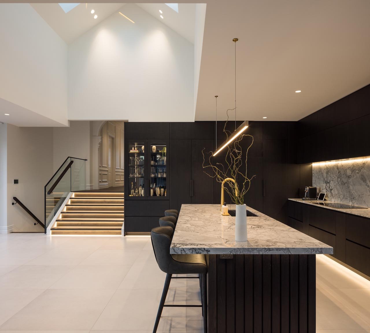 Modern kitchen in dark oak with marble island and brass blade light above the island.
