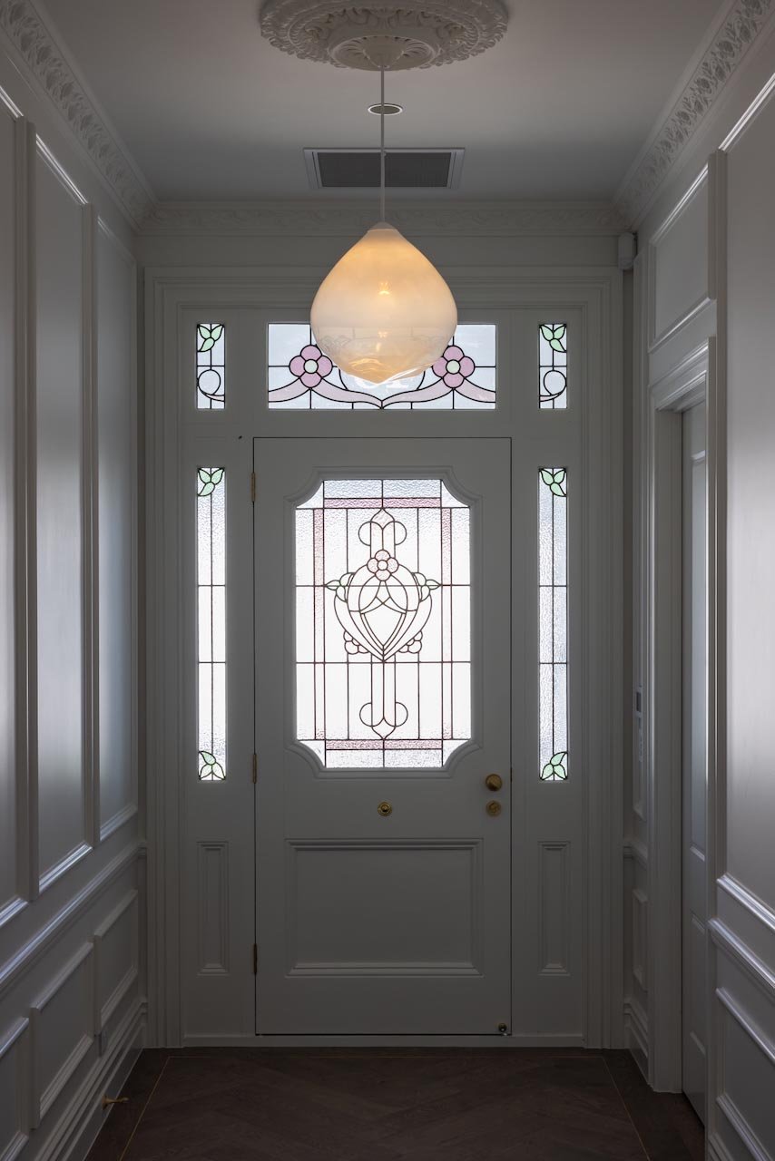 Villa hallway with a pendant light and a stained glass front door.