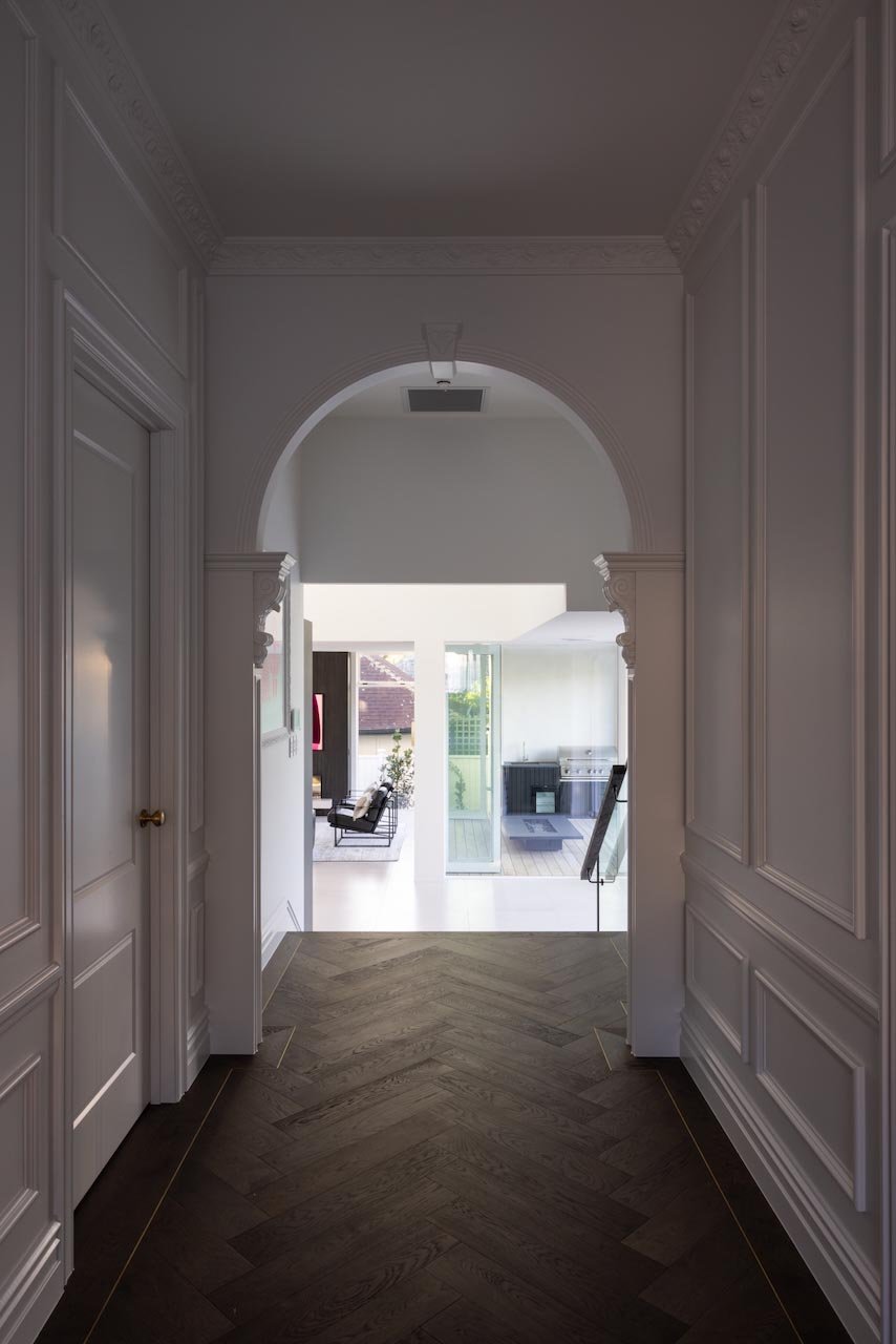 Villa hallway with herringbone oak flooring and white panelled walls.