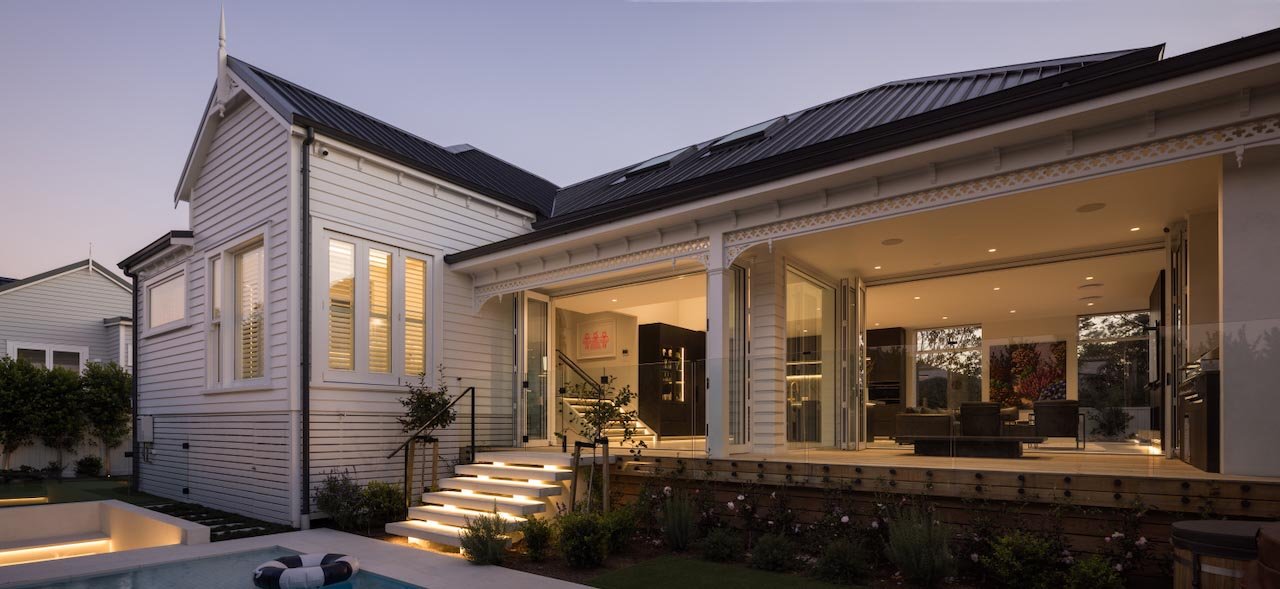 Exterior of villa lit up from inside showing the doors open to a verandah.