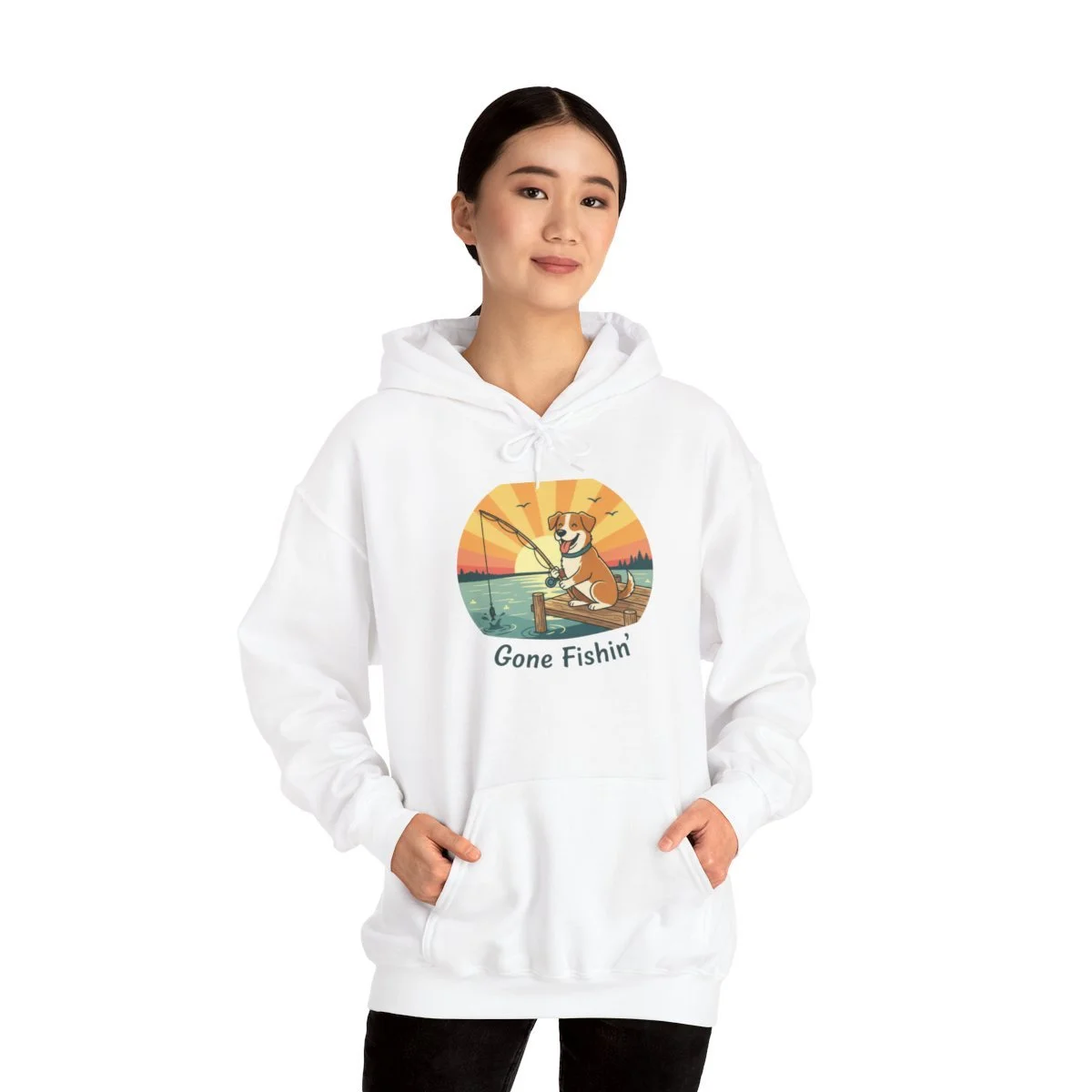 Young woman wearing a white hoodie with a colorful cartoon dog fishing at sunset, with the text "Gone Fishin'".