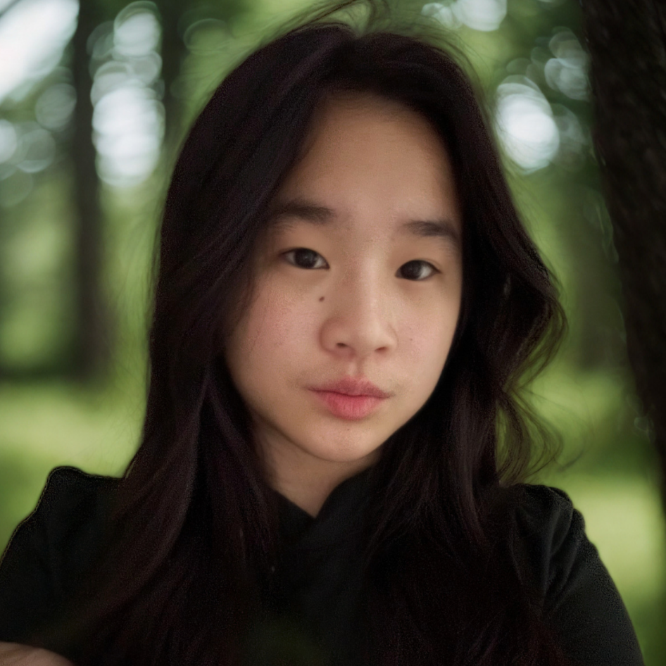 Portrait of a young Asian woman with long dark hair, standing outdoors with a blurred green forest background.