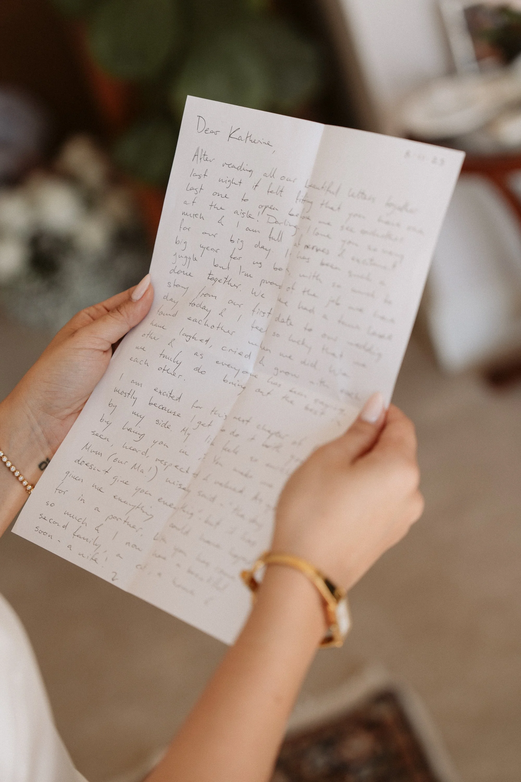 Person holding a handwritten letter with blurred indoor background.