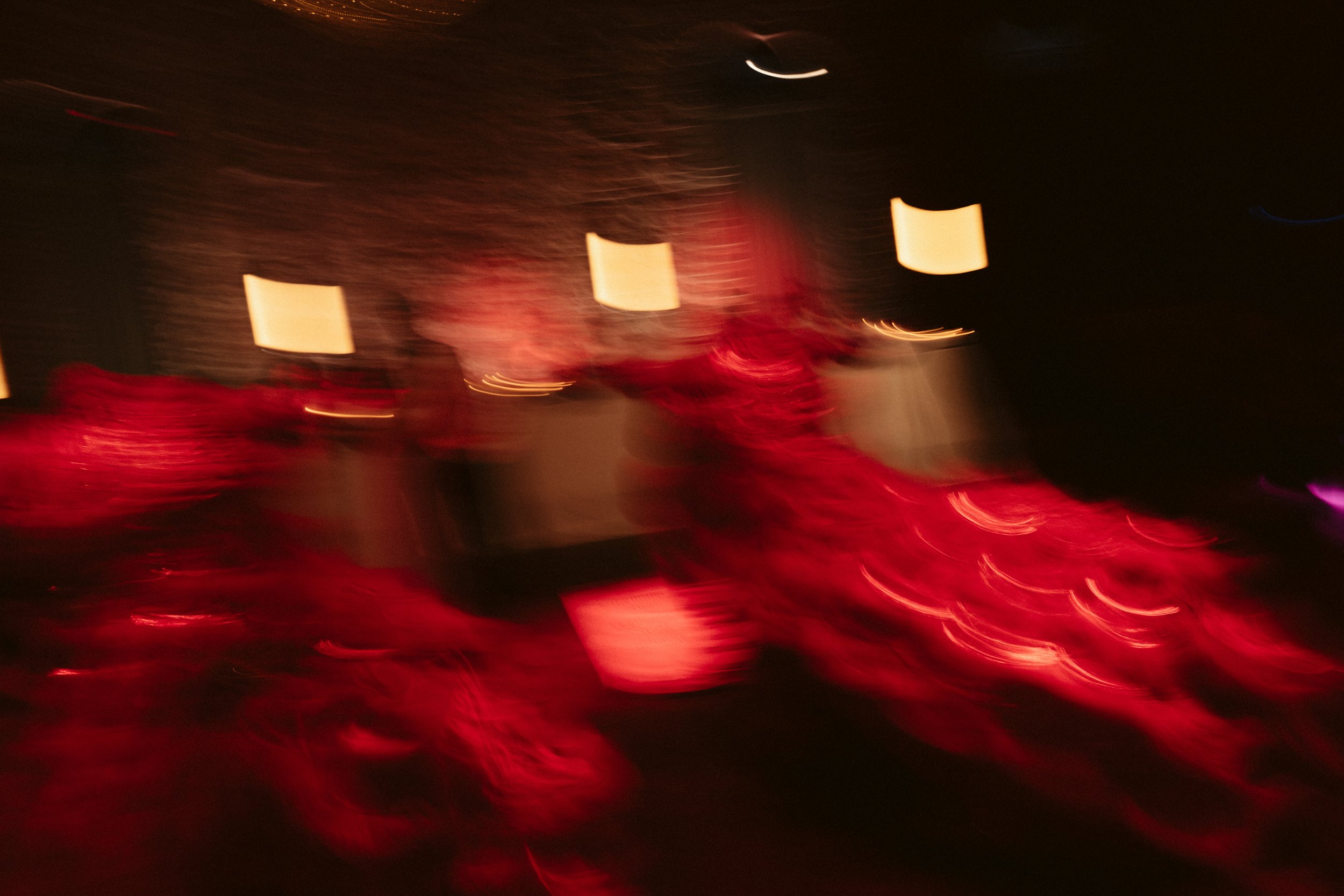 Blurred image with red and black colors, likely featuring out-of-focus objects and lights.