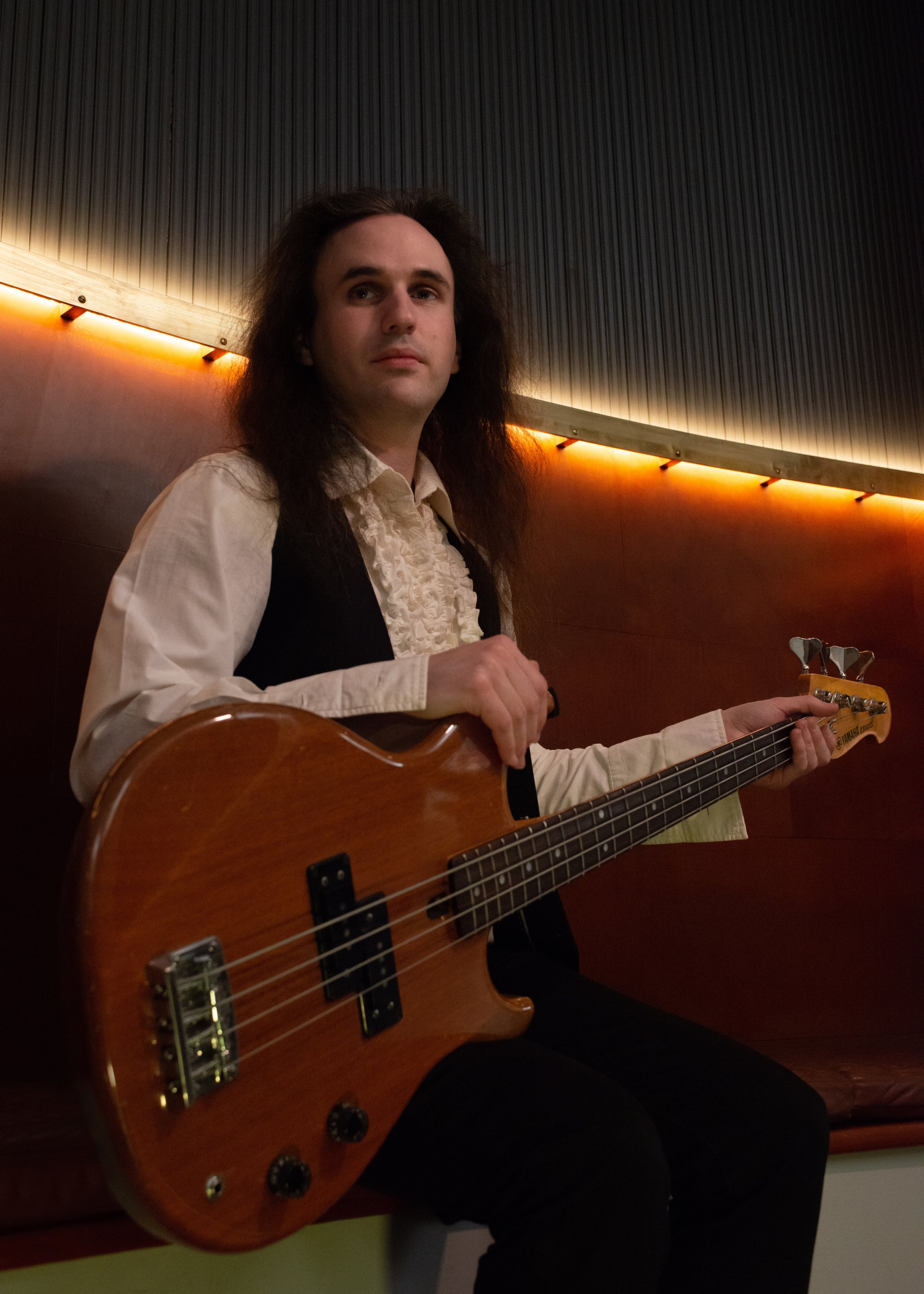 Person holding a bass guitar in a room with dim lighting.
