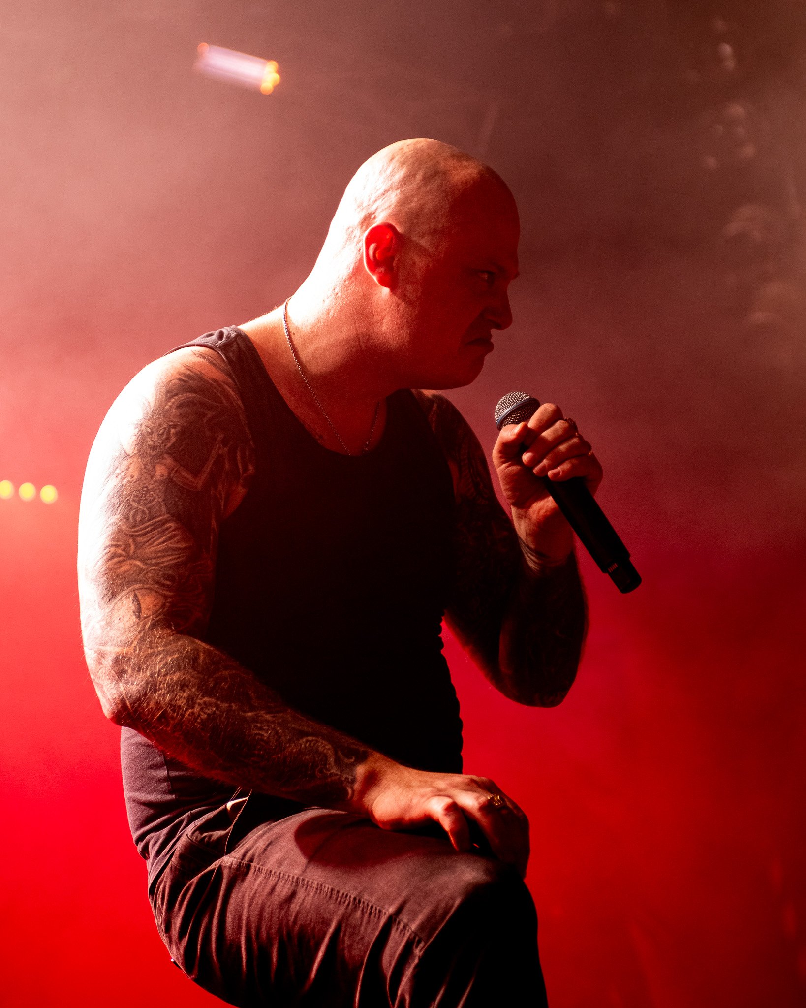 Man with tattoos performing on stage with microphone