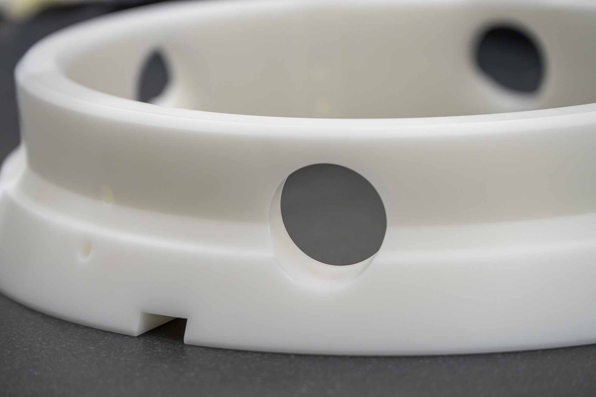Close-up of a white plastic object with circular holes, possibly a component of a device or appliance.