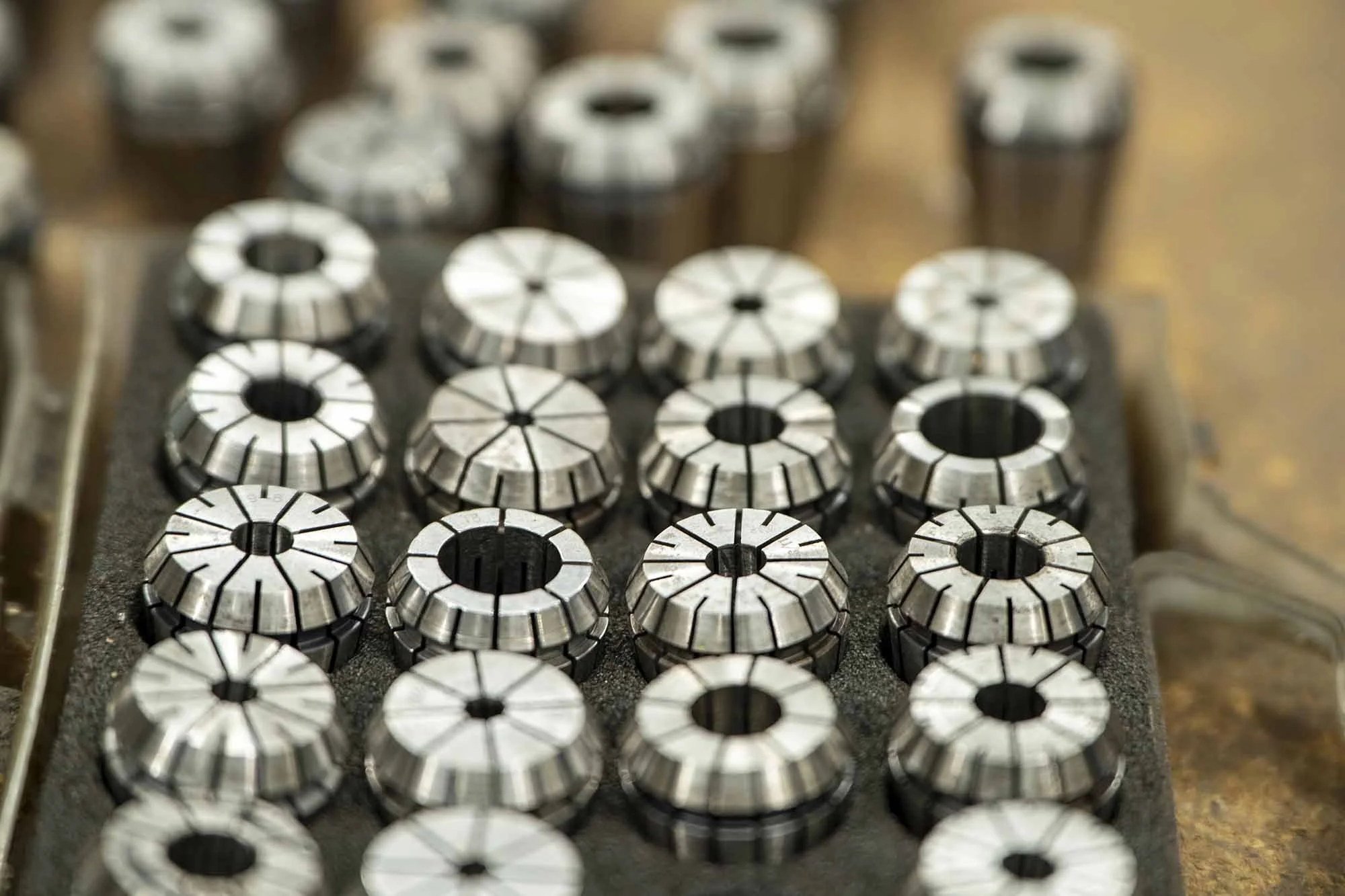 A set of metal collets arranged on a foam tray, used for holding small workpieces or tools in machining.
