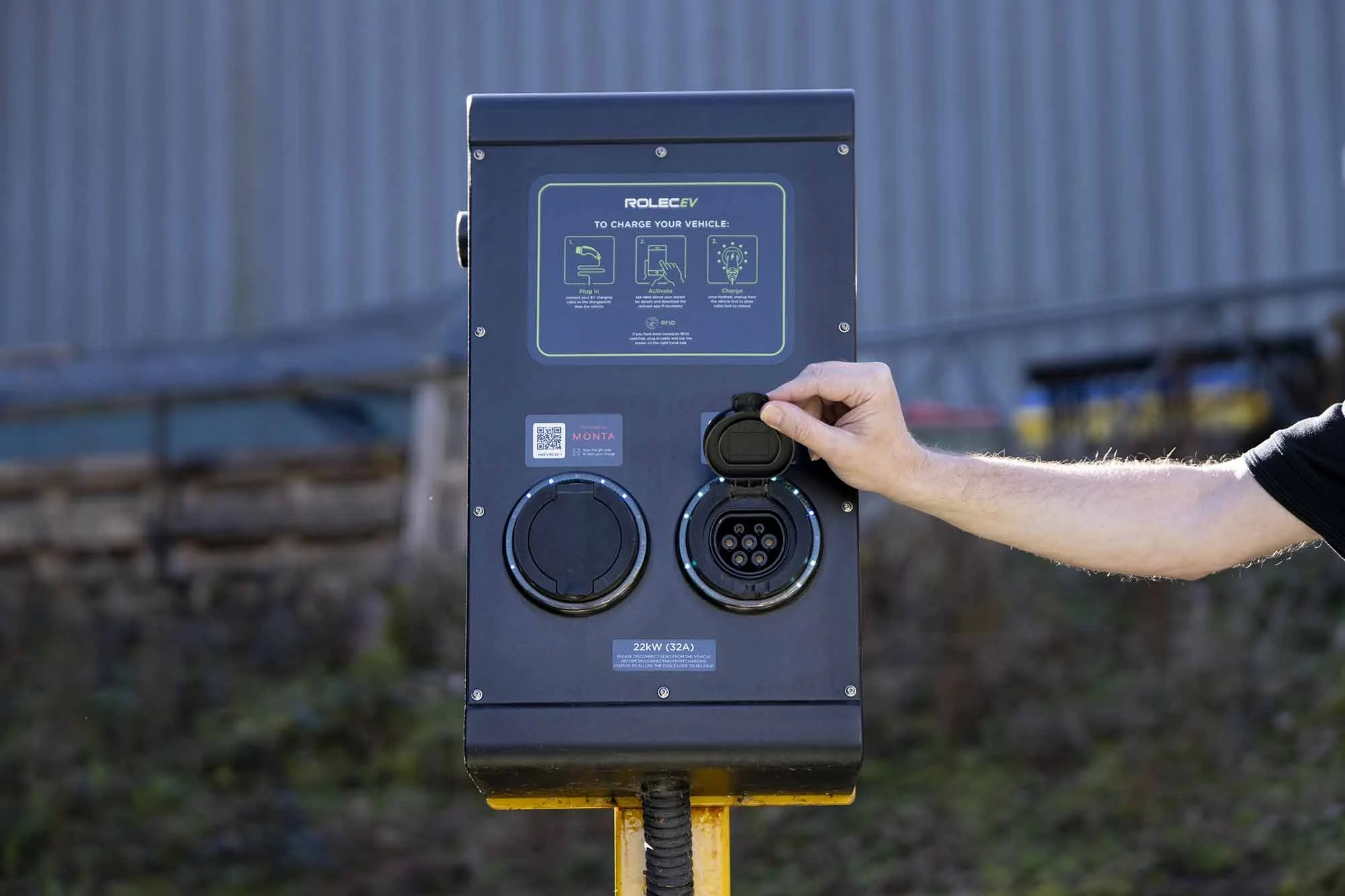 A person plugging an electric vehicle charging cable into an electric vehicle charging station in the WKW carpark.