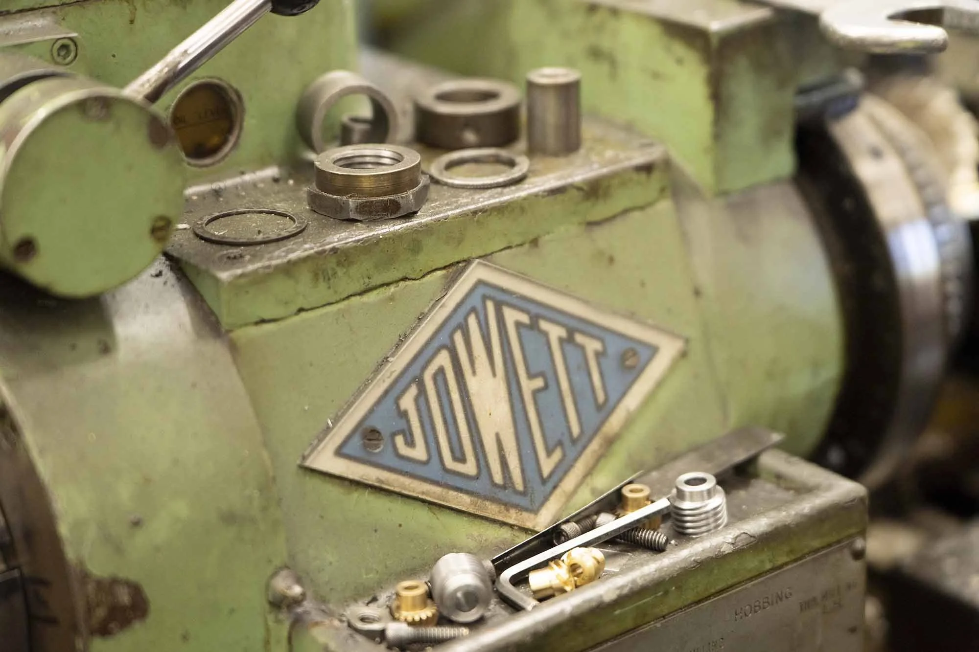 Close-up of a green industrial machine with metal parts scattered on it, and a JOWETT logo.