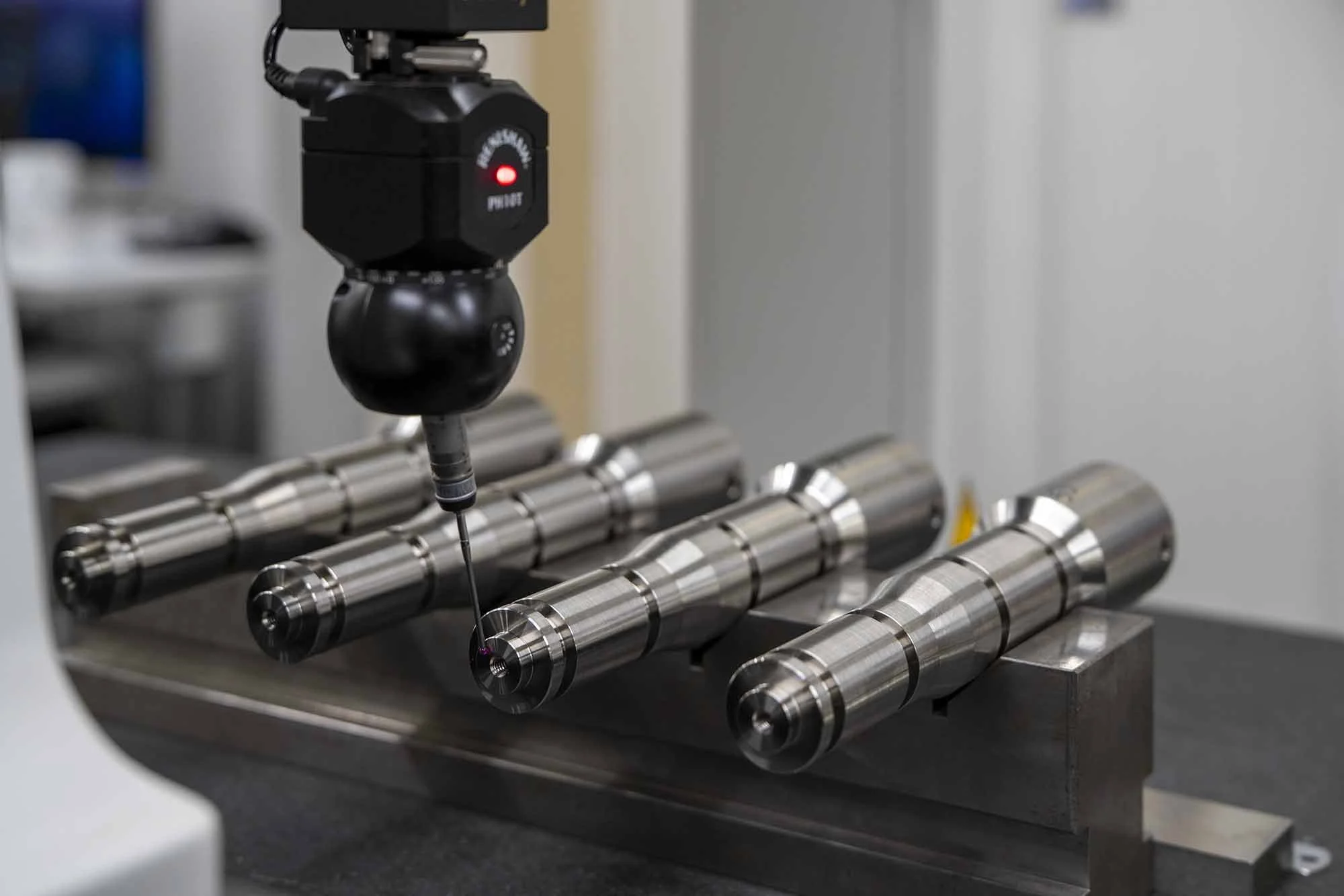 A precision measurement device with a probe touching a metallic cylindrical object on a black surface.