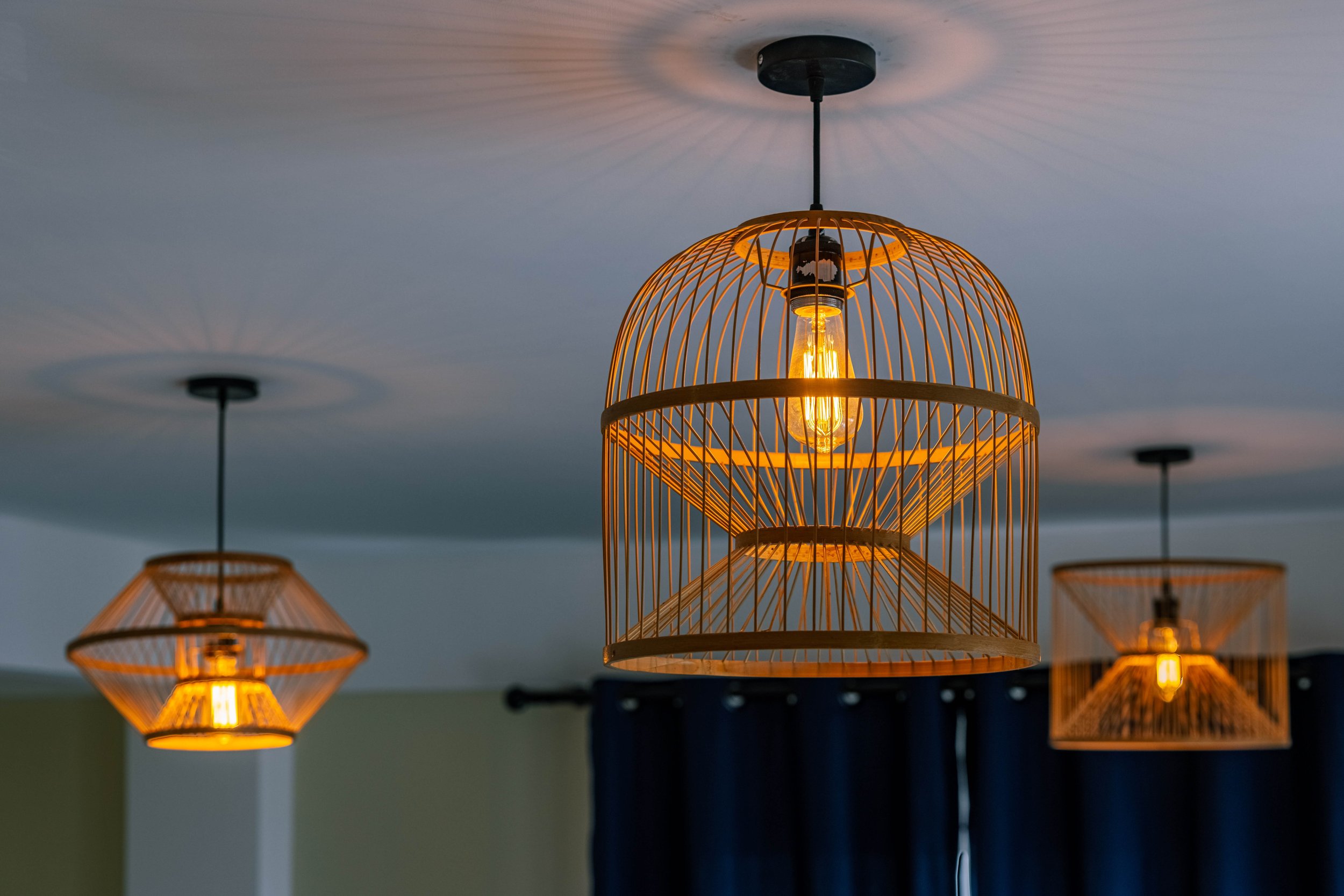 Hanging lights with a wooden cage design, turned on and emitting warm glow, cast shadows on the ceiling.