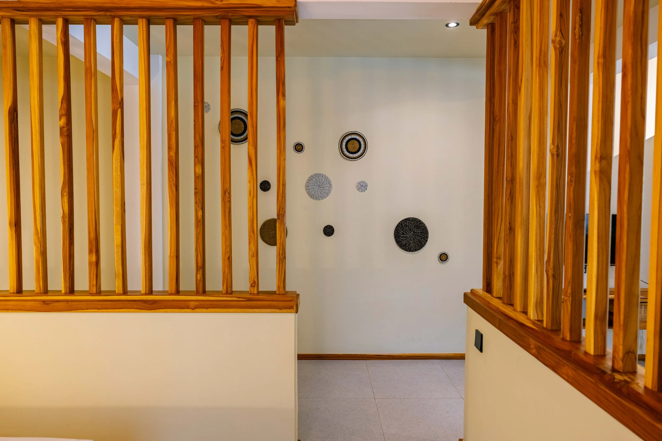 View from above of a staircase with wooden railings and decorative wall art on a white wall.
