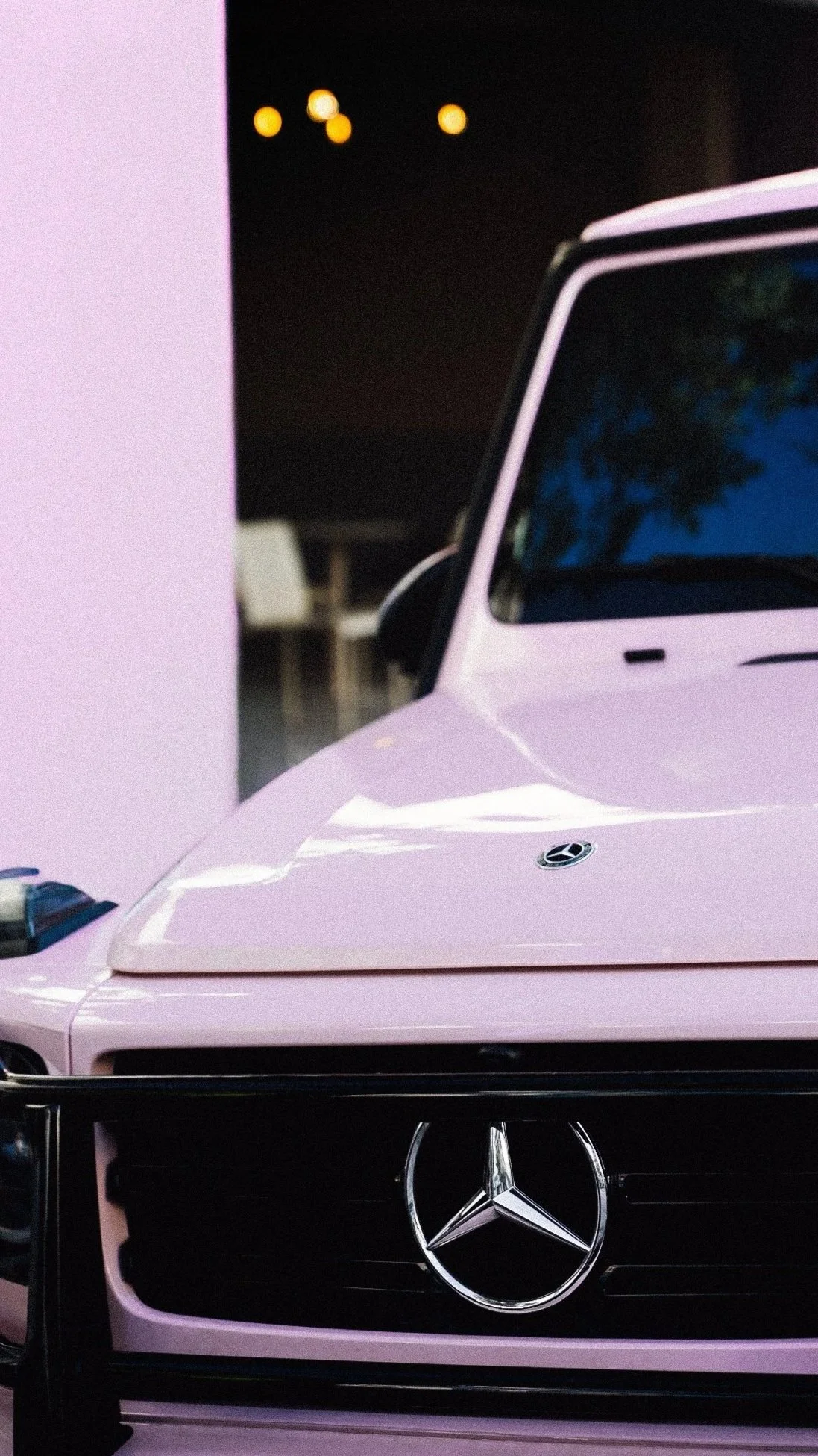 Close-up of a pink Mercedes-Benz car showing the front grille and hood, with the Mercedes-Benz logo visible.