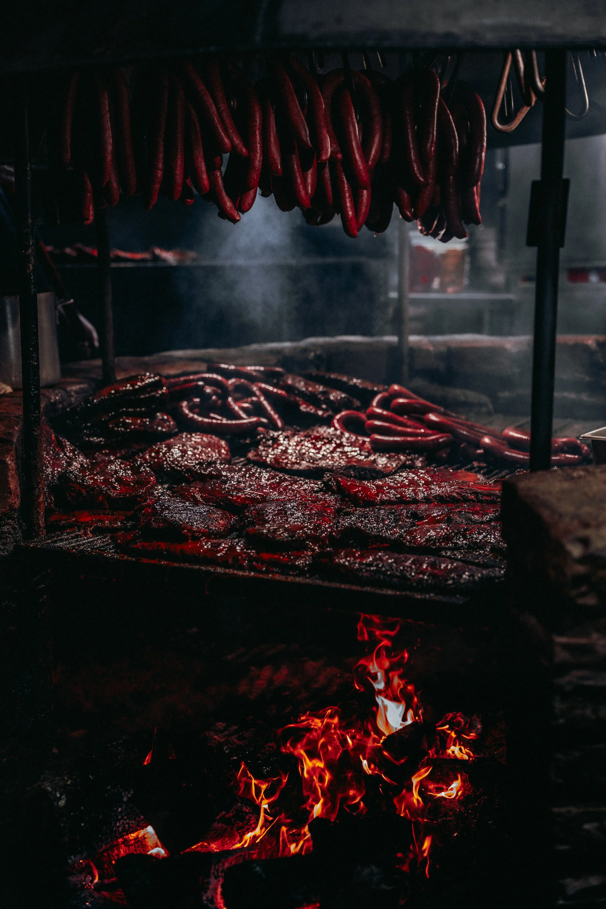 Meat and sausages grilling over an open flame at a barbecue.