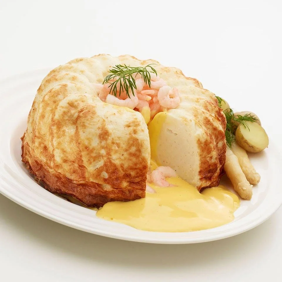 Traditional English-style fish pie with a golden pastry crust, filled with chunks of white fish, shrimp, and herbs, served with boiled baby potatoes and white asparagus.