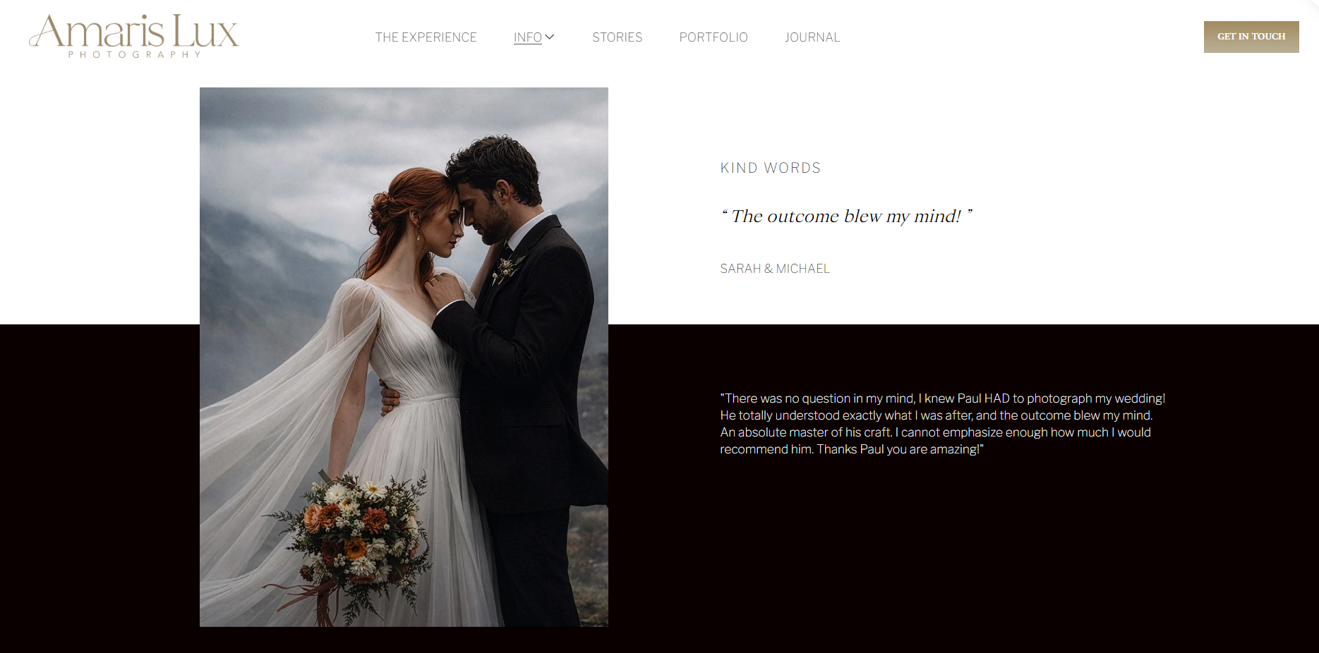 A bride and groom stand close together, touching foreheads in an outdoor mountain setting during a cloudy day. The bride wears a white wedding gown with flowing sleeves, holding a bouquet of flowers. The groom wears a black suit and tie.