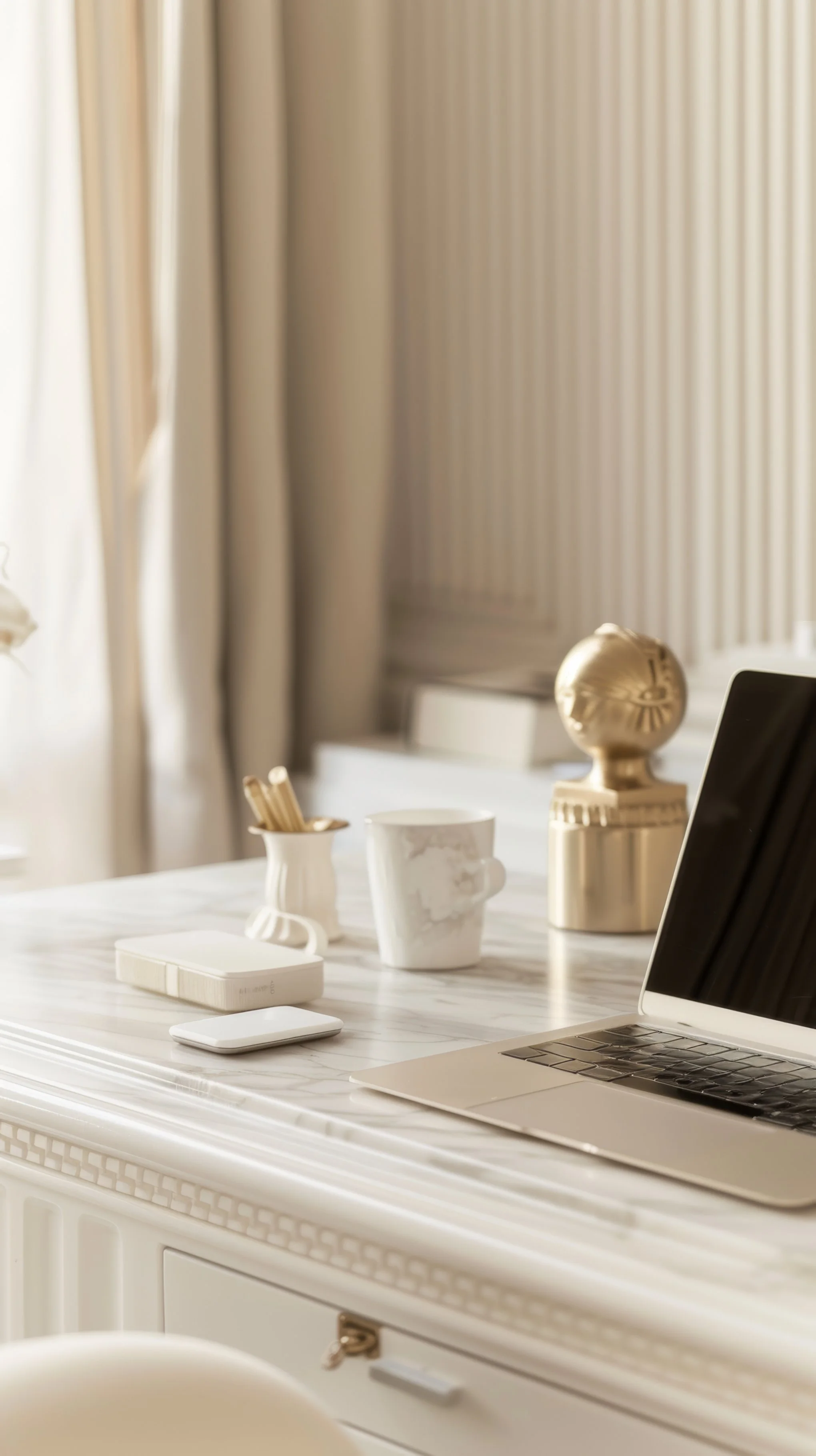 A white desk with a laptop, wireless mouse, and various decorative items and containers on it, with a beige curtain background.