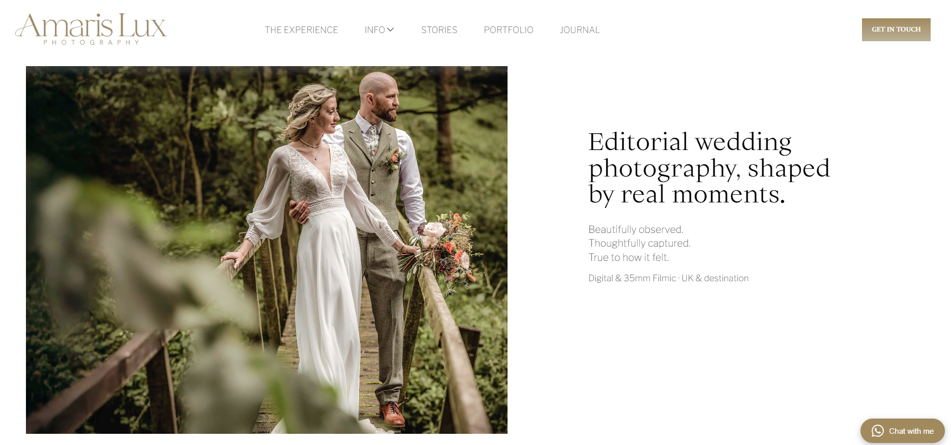 A bride and groom standing on a wooden bridge in a forest during a wedding photo shoot. The bride is wearing a white dress and holding a bouquet; the groom is dressed in a gray vest, white shirt, and tie.