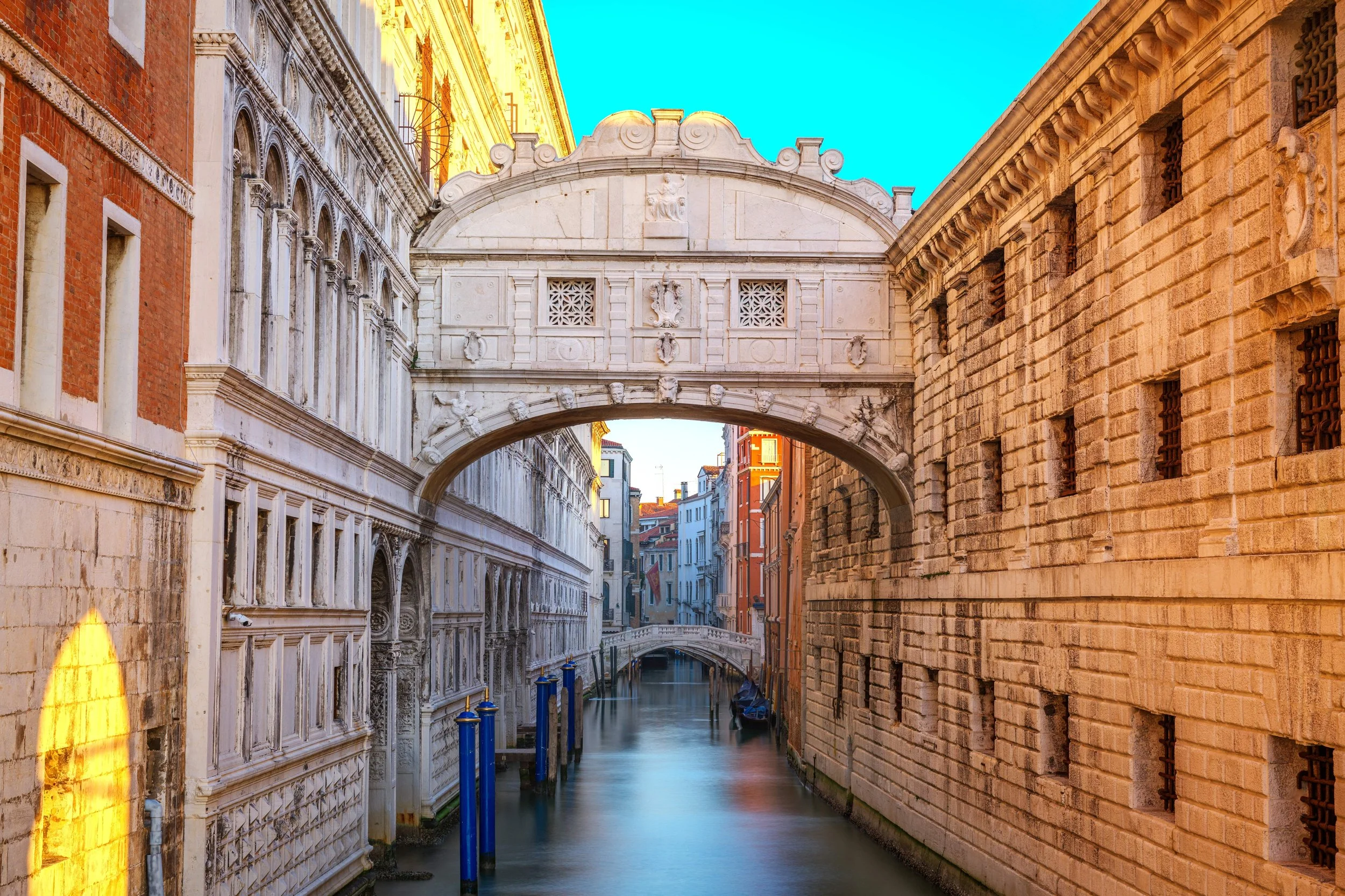 Venetian canal with historic buildings and a white bridge arching over the water, in Venice, Italy.
