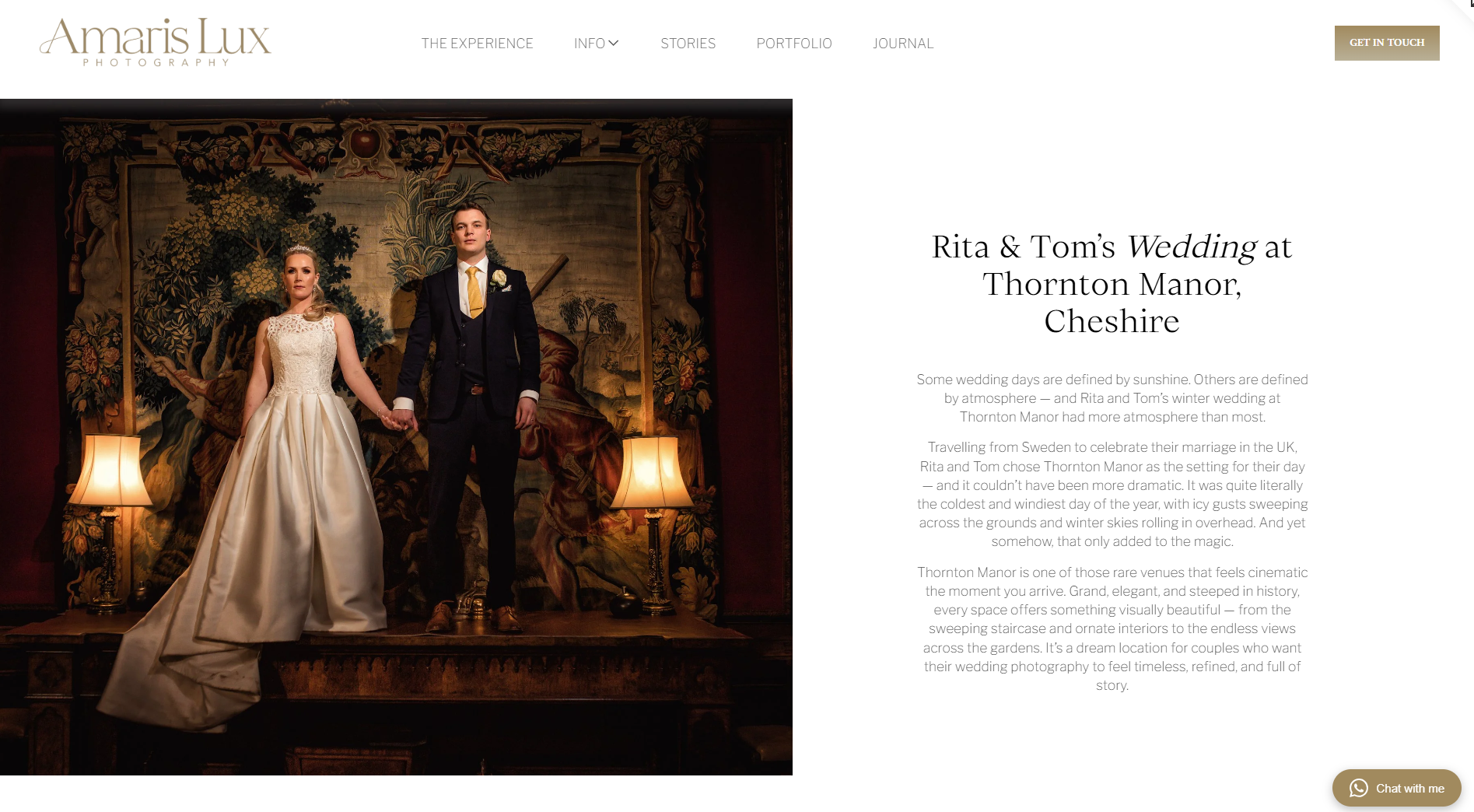 Wedding couple standing on a stage with a tapestry backdrop, holding hands. The bride wears a white gown with a long train, and the groom wears a dark suit with a white shirt and yellow tie. There are two table lamps on either side of them.