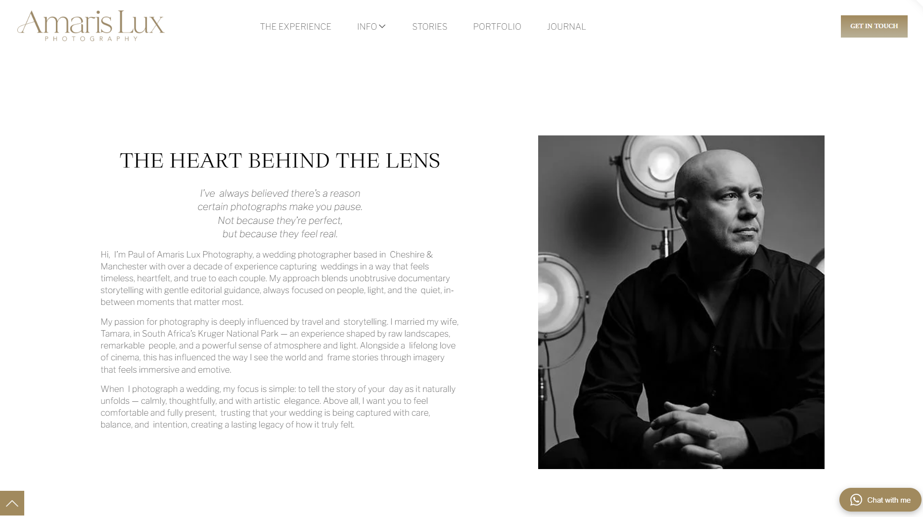A professional black and white portrait photograph of a bald man with light skin, sitting with his hands clasped in front of him, in front of studio lights, on a photo studio backdrop. The website header includes the name 'Amaris Lux Photography' and navigation links.