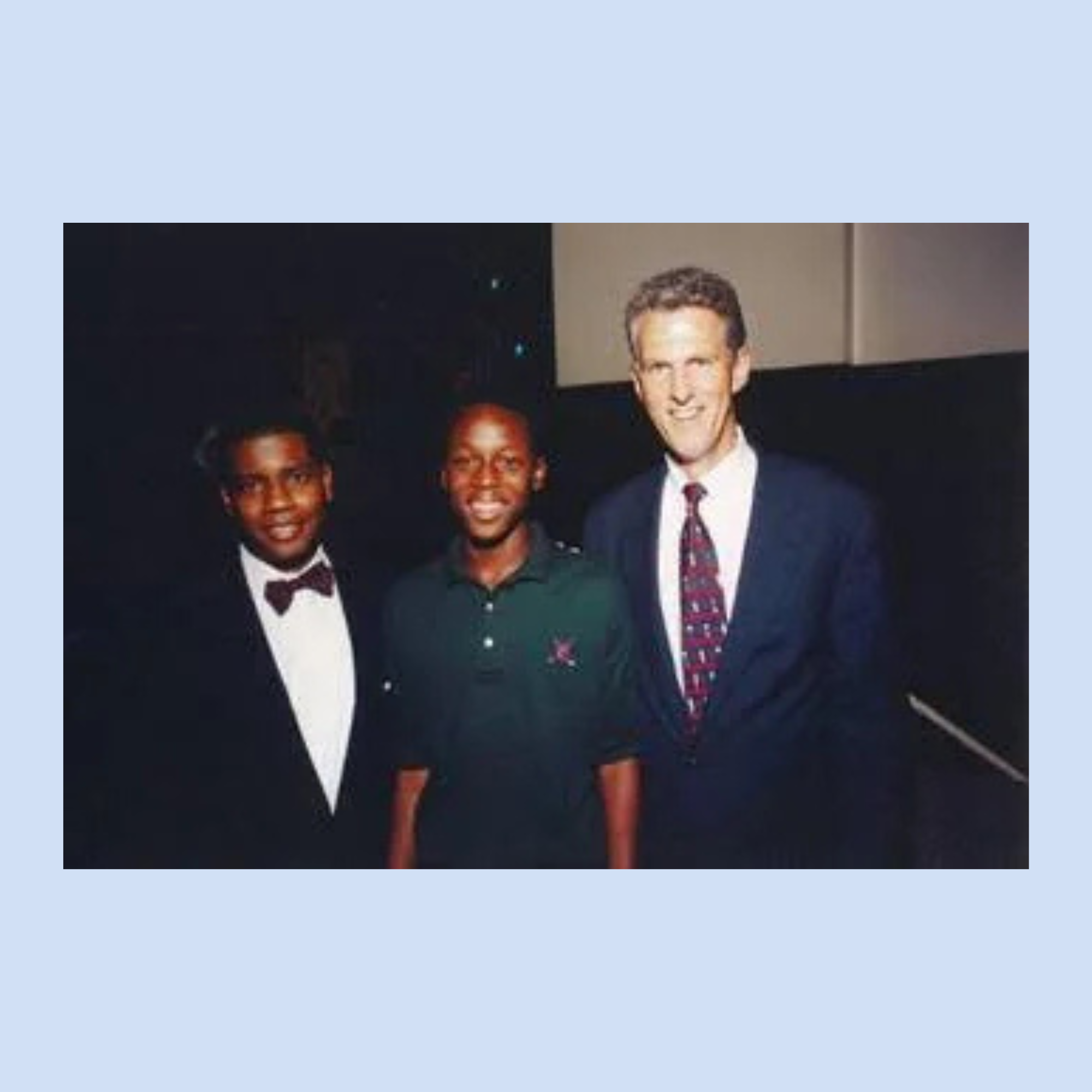 Three individuals posing together at an event, including two young men and an adult mentor figure in formal attire.