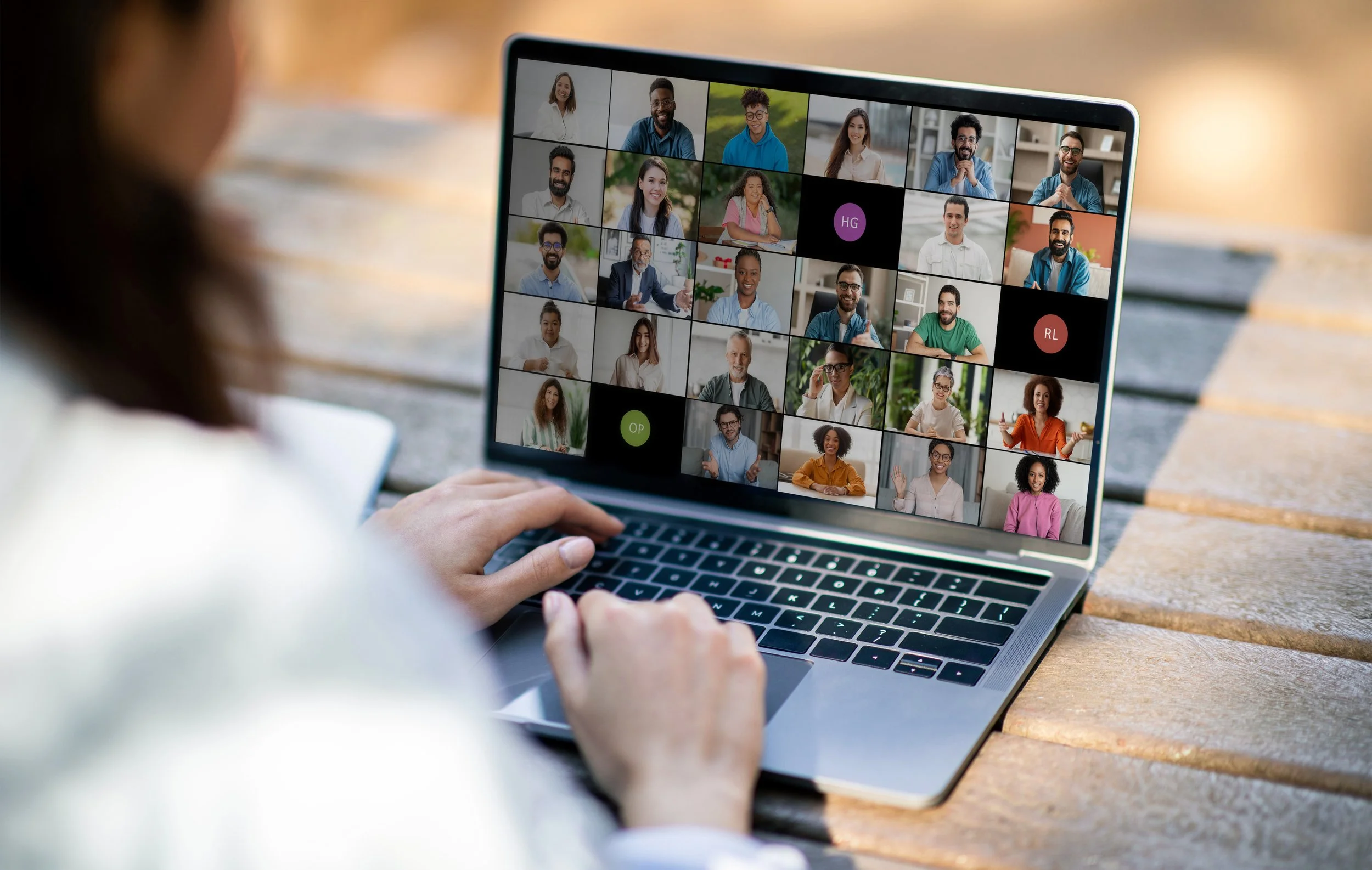 Person using laptop for a video conference with multiple participants on screen.