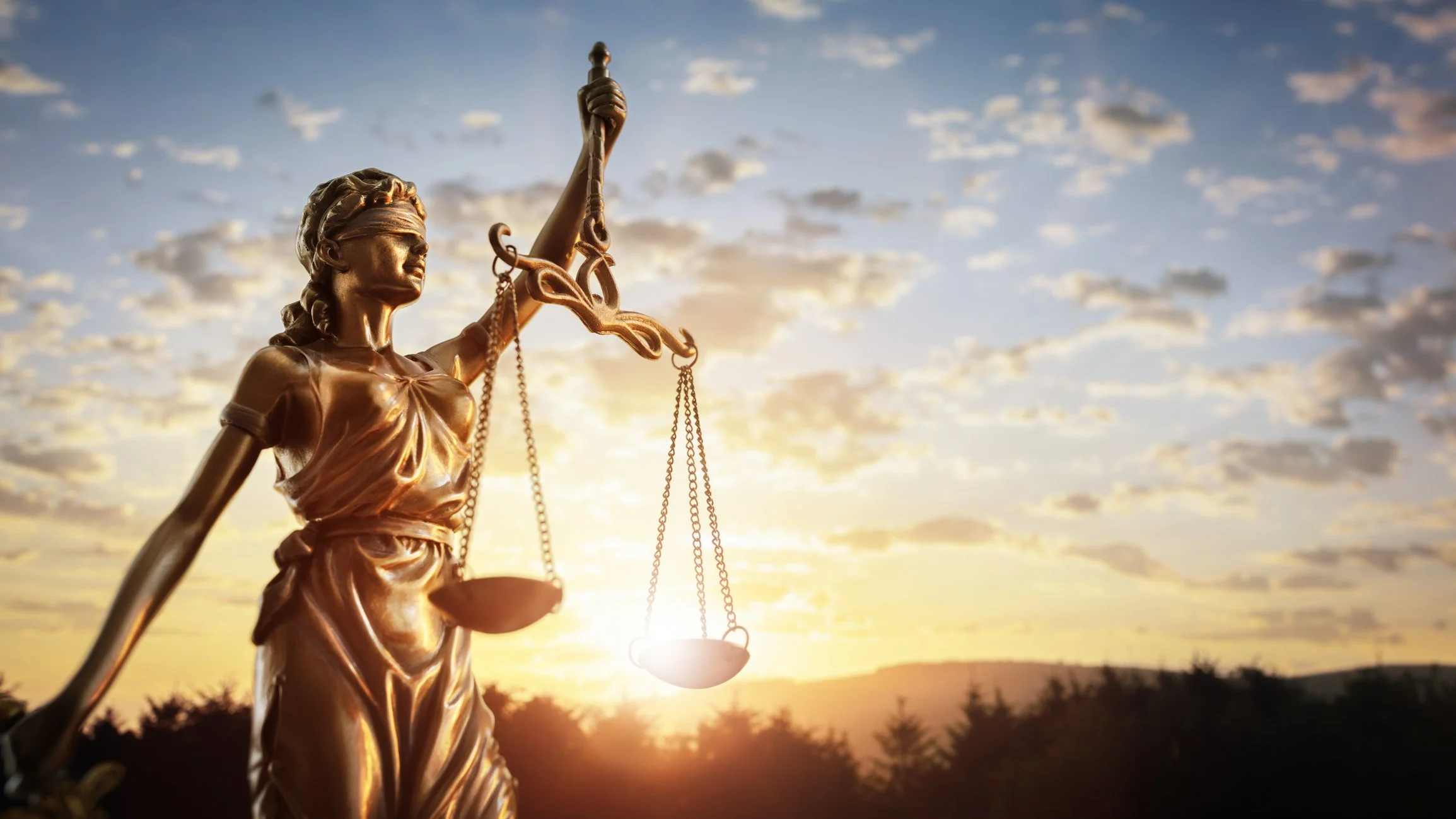 Lady Justice with the sun shining brightly in the background.