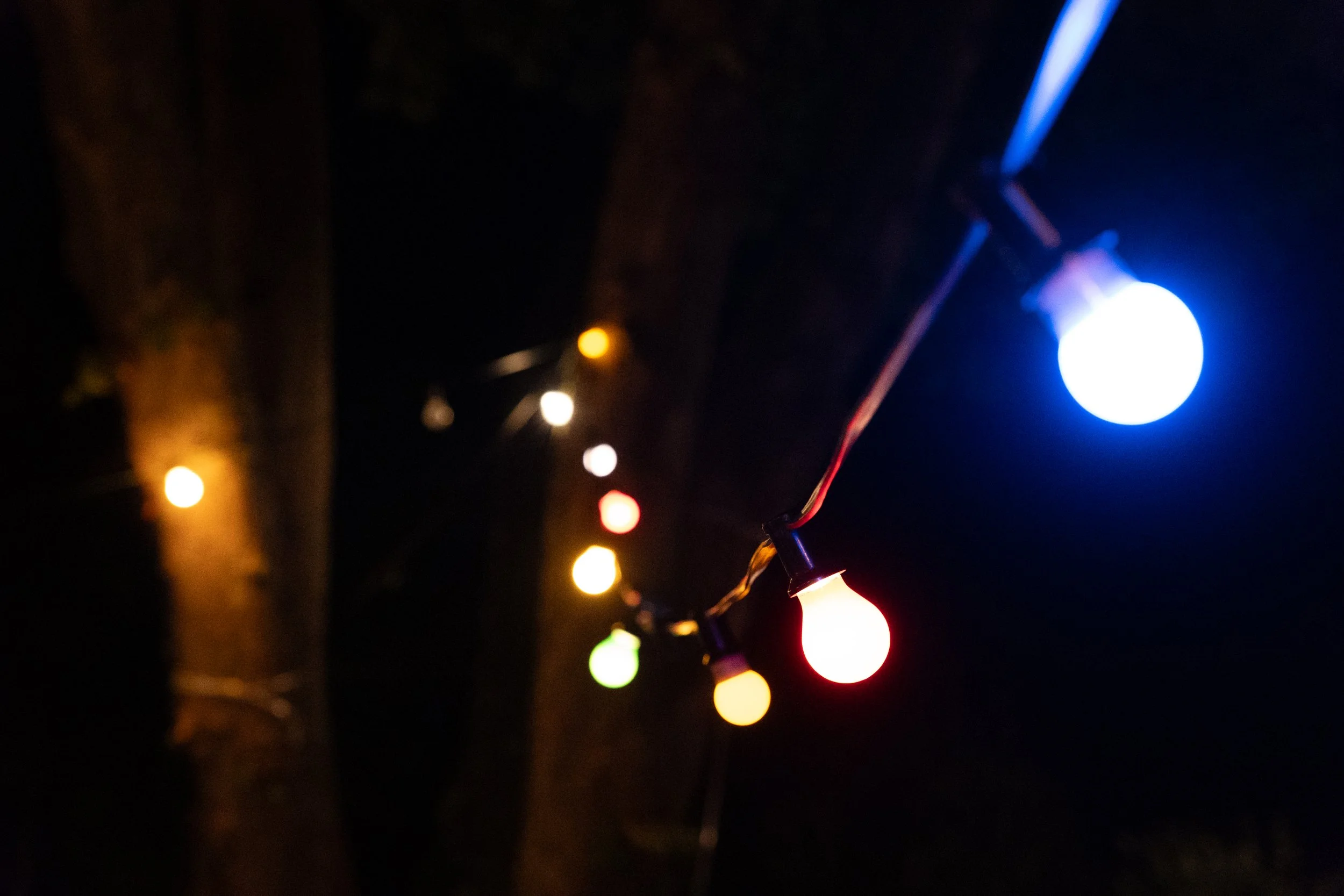 Bunte Lichterketten leuchten bei Nacht im dunklen Hintergrund.