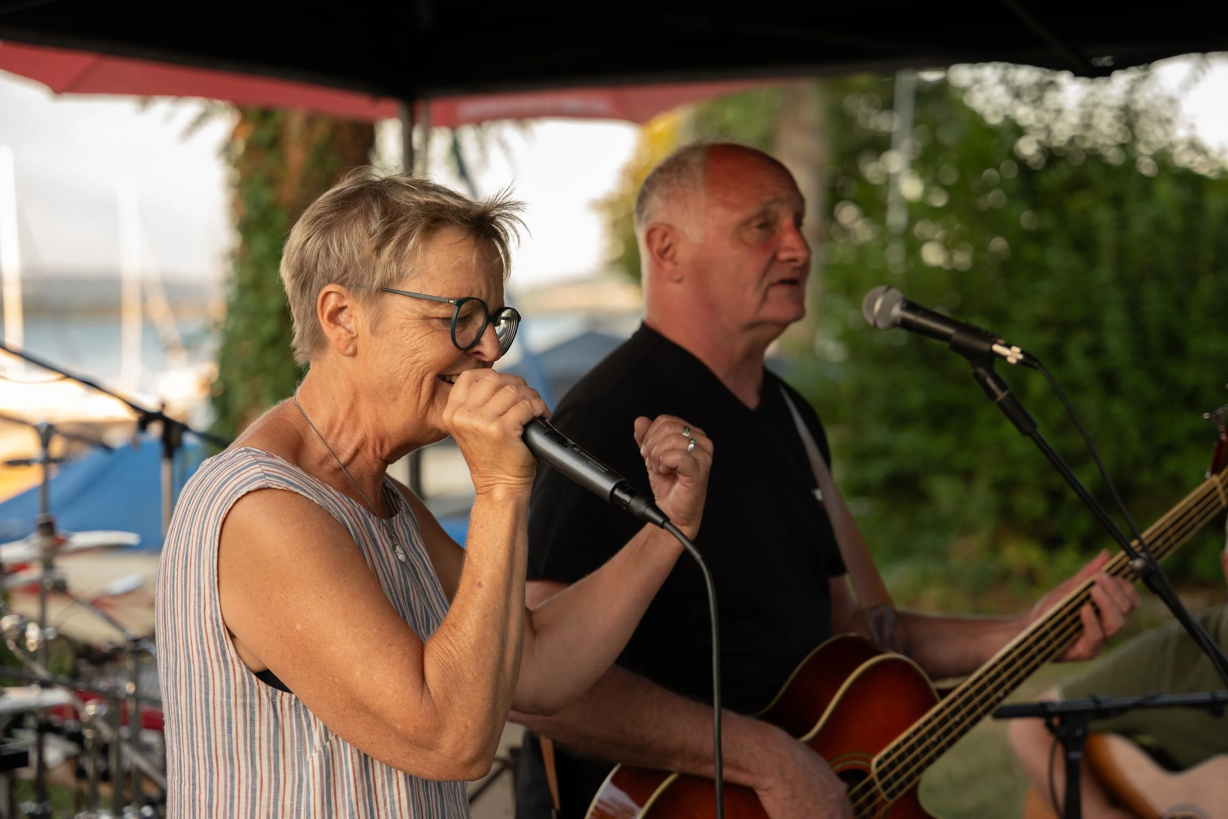 Älteres Paar, singend und Gitarre spielend bei einem Outdoor-Konzert.