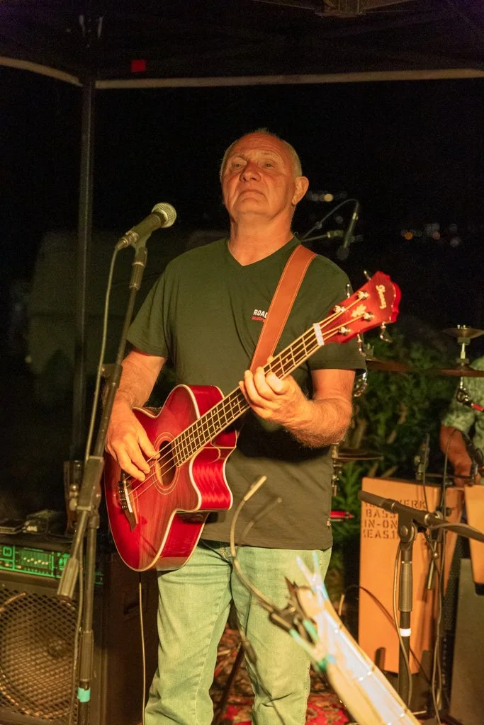 Ein älterer Mann spielt akustische Gitarre auf einer Bühne bei einem Live-Konzert.