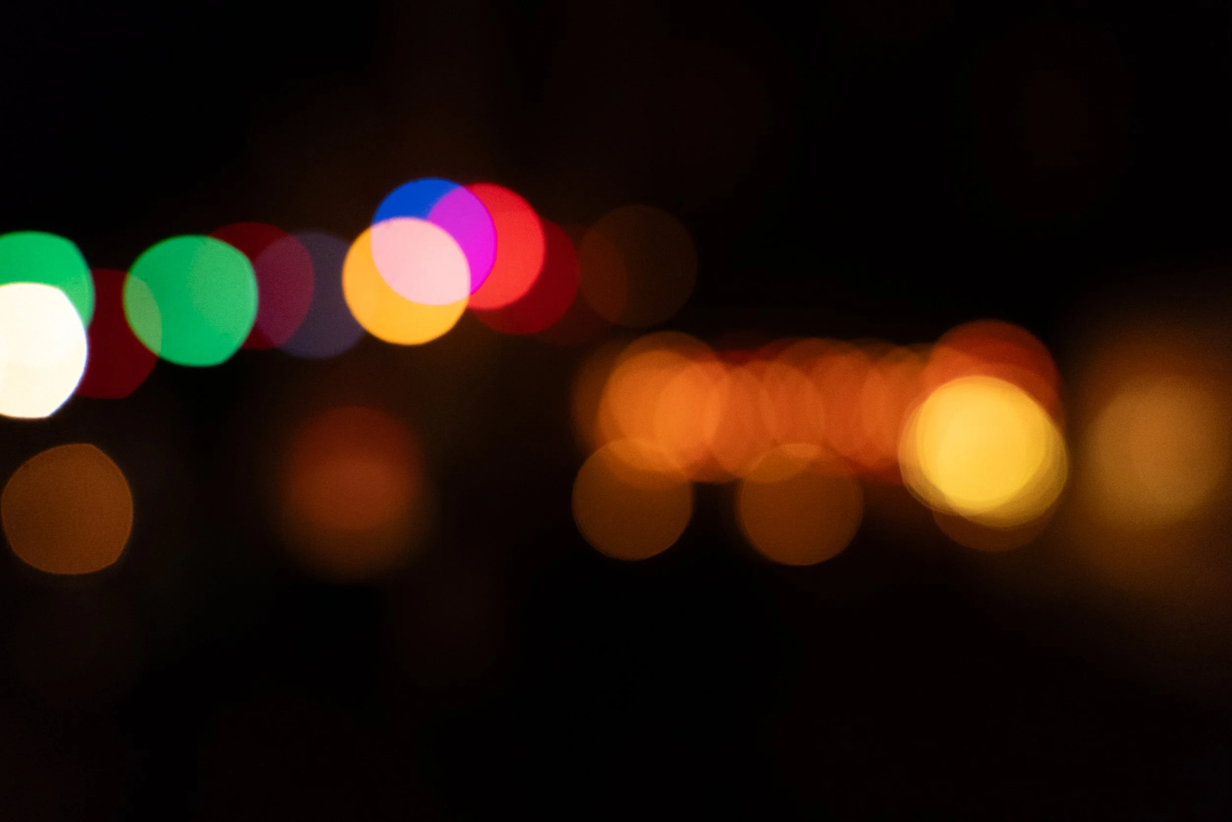 Bunte Lichter auf einer dunklen Straße, unscharf und in Bokeh-Optik