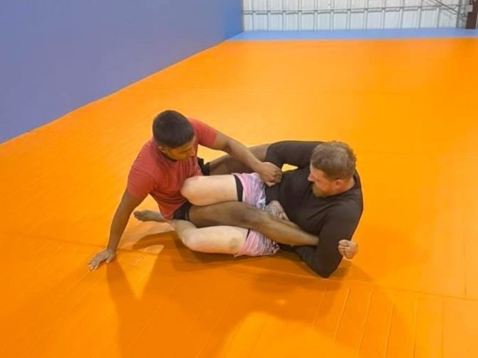Two men practicing Brazilian Jiu-Jitsu on an orange mat at Fusion Martial Arts of Warren, Ohio