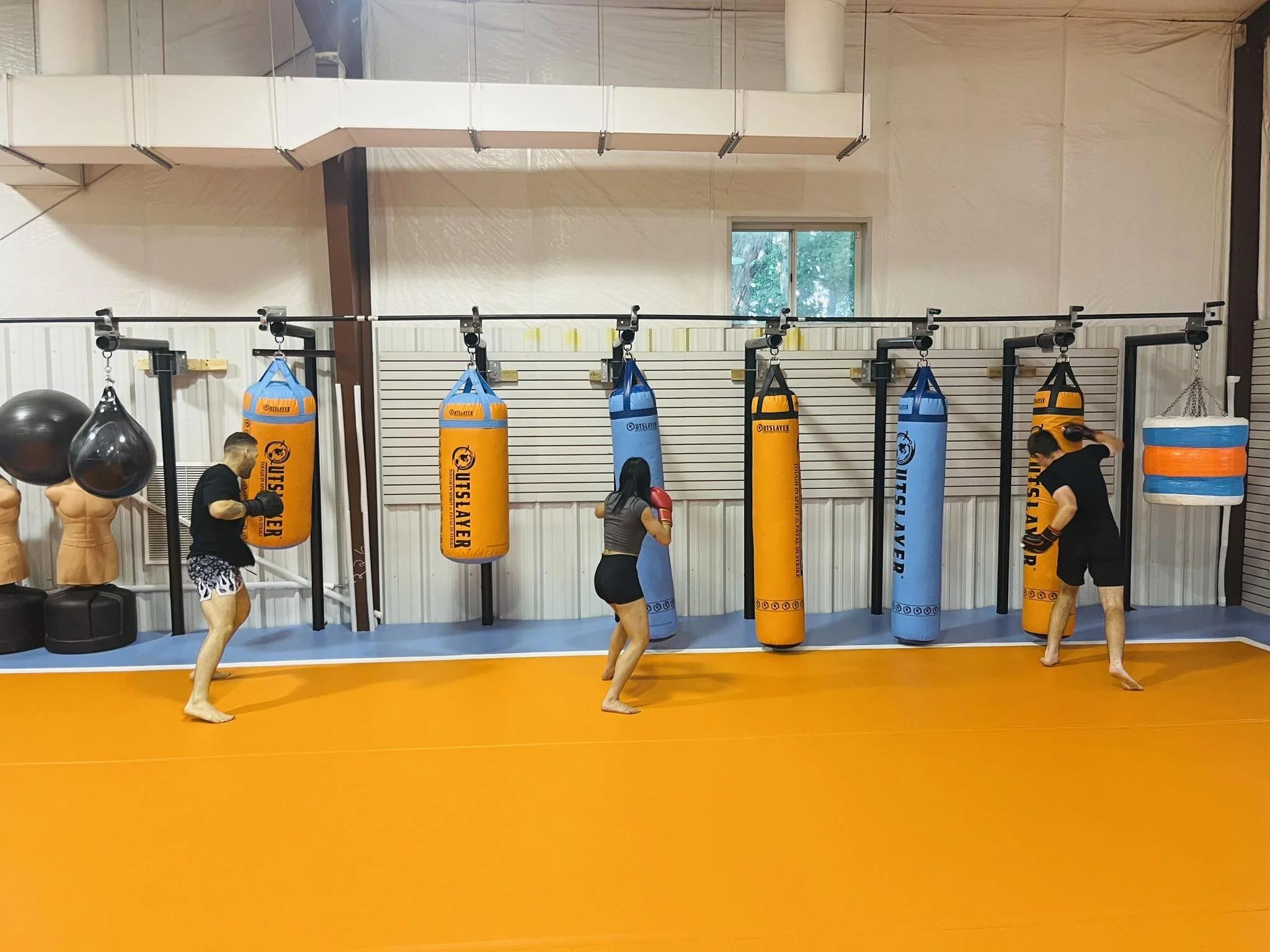 People practicing muay thai striking in a gym with punching bags.