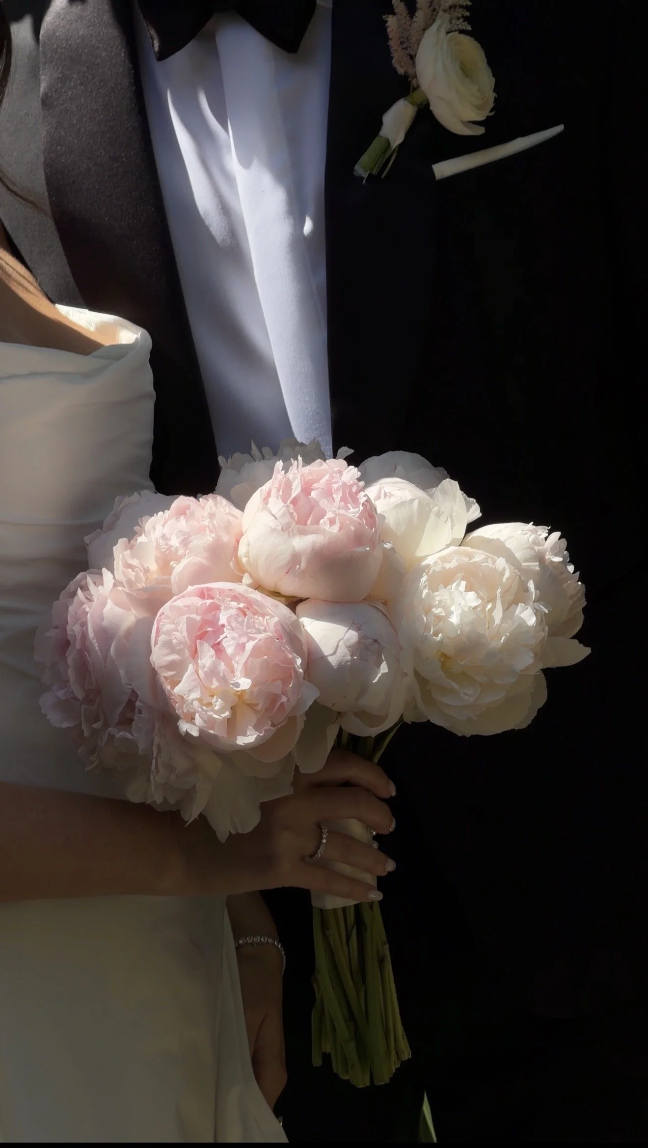 A black-and-white photo of a bride and groom on their wedding day, with the bride's veil covering part of the groom's face.