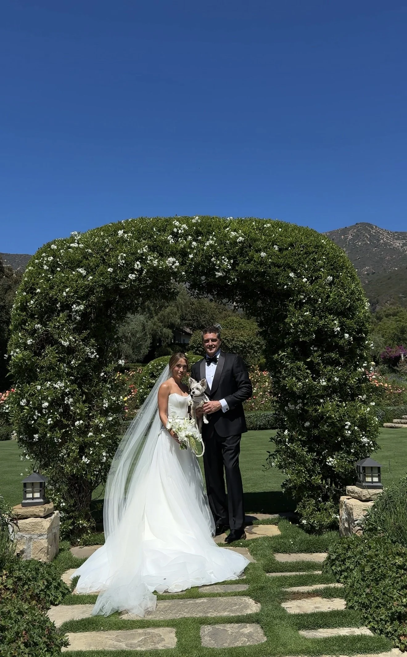 Close-up of a couple embracing, with the woman wearing a white dress and the man in a black suit.