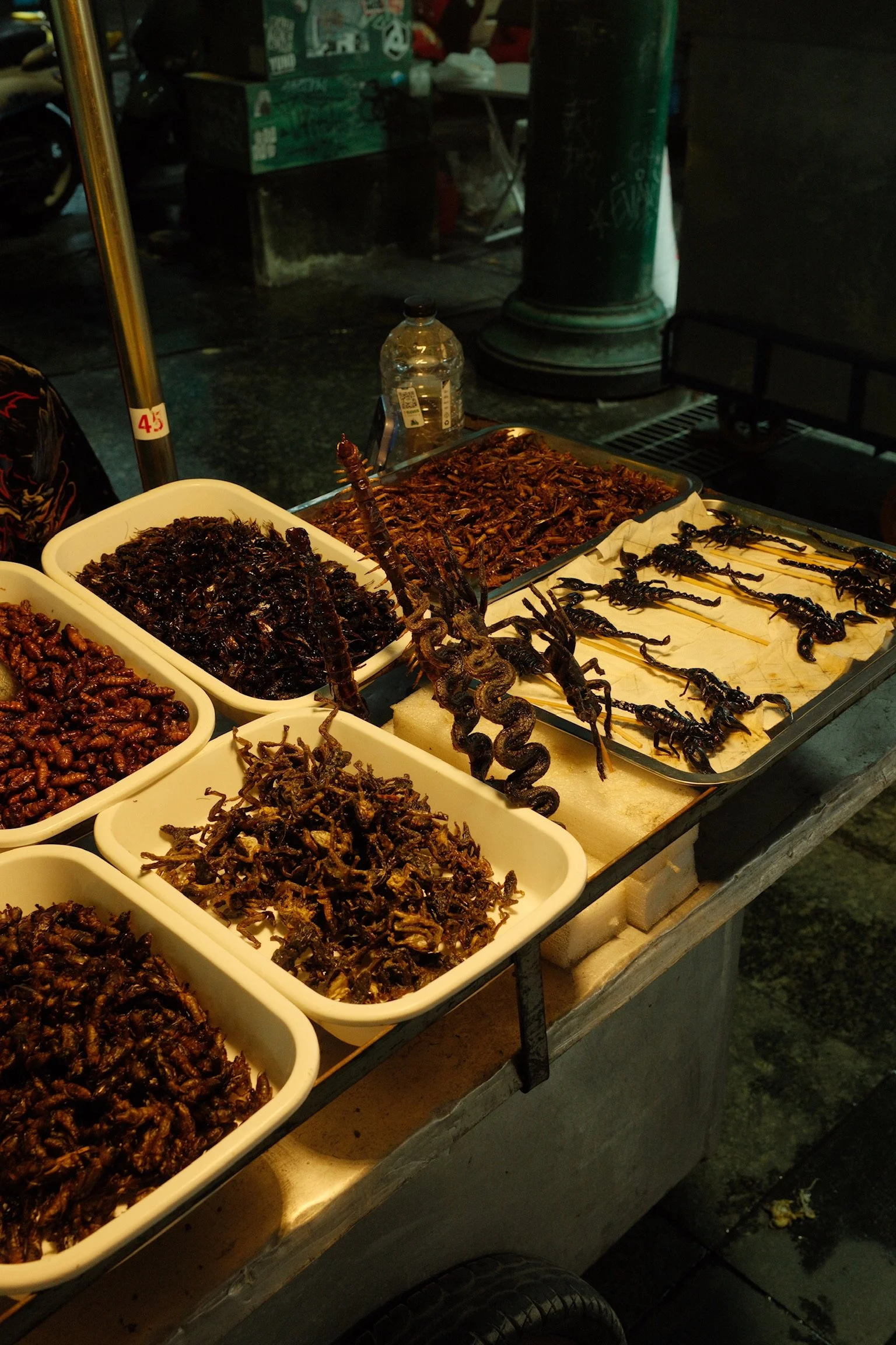 Een straatkraam in Bangkok met diverse gekookte insecten en insectenspiezen.