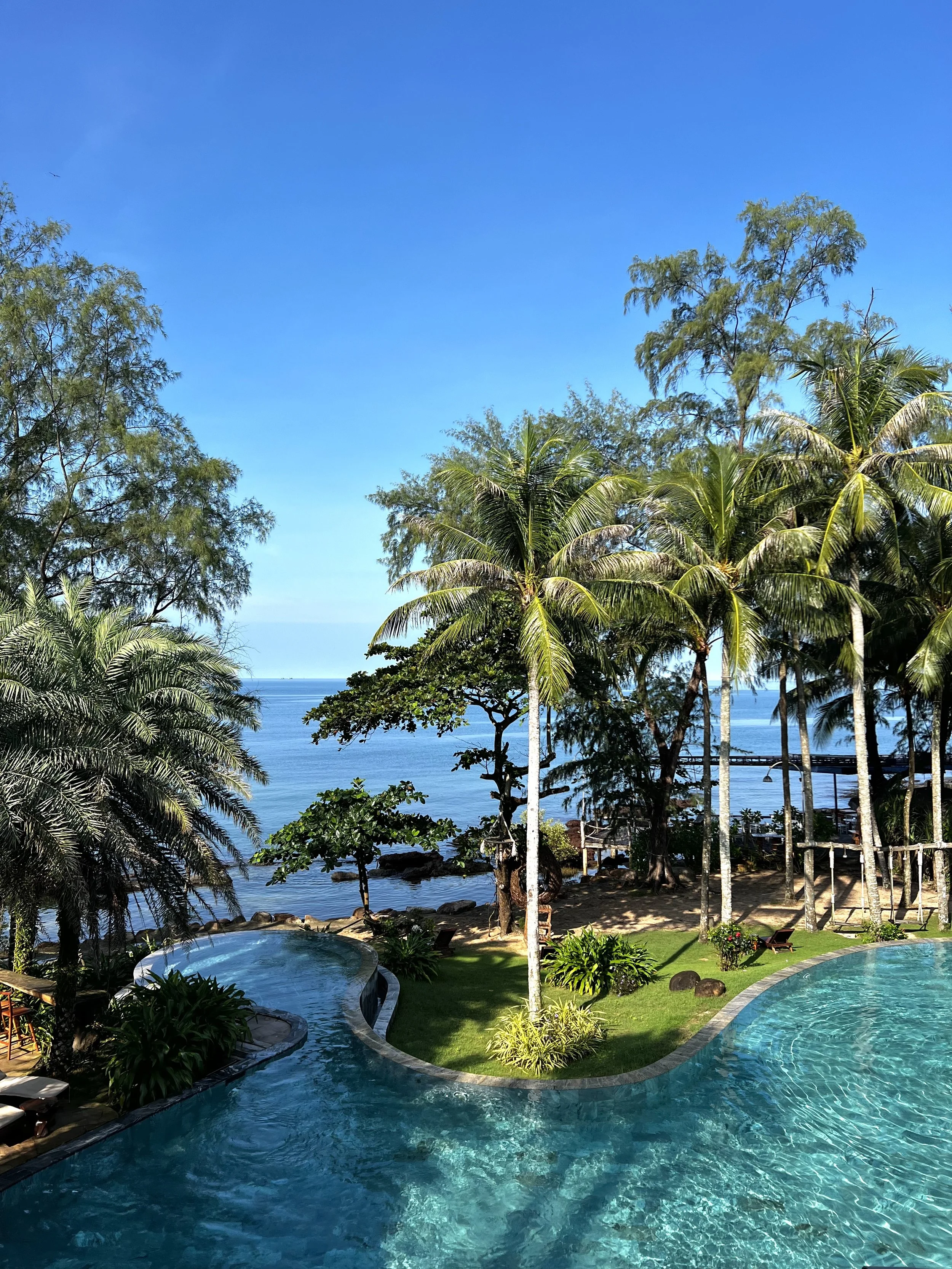 zwembad met palmbomen en uitzicht op de oceaan onder een blauwe lucht