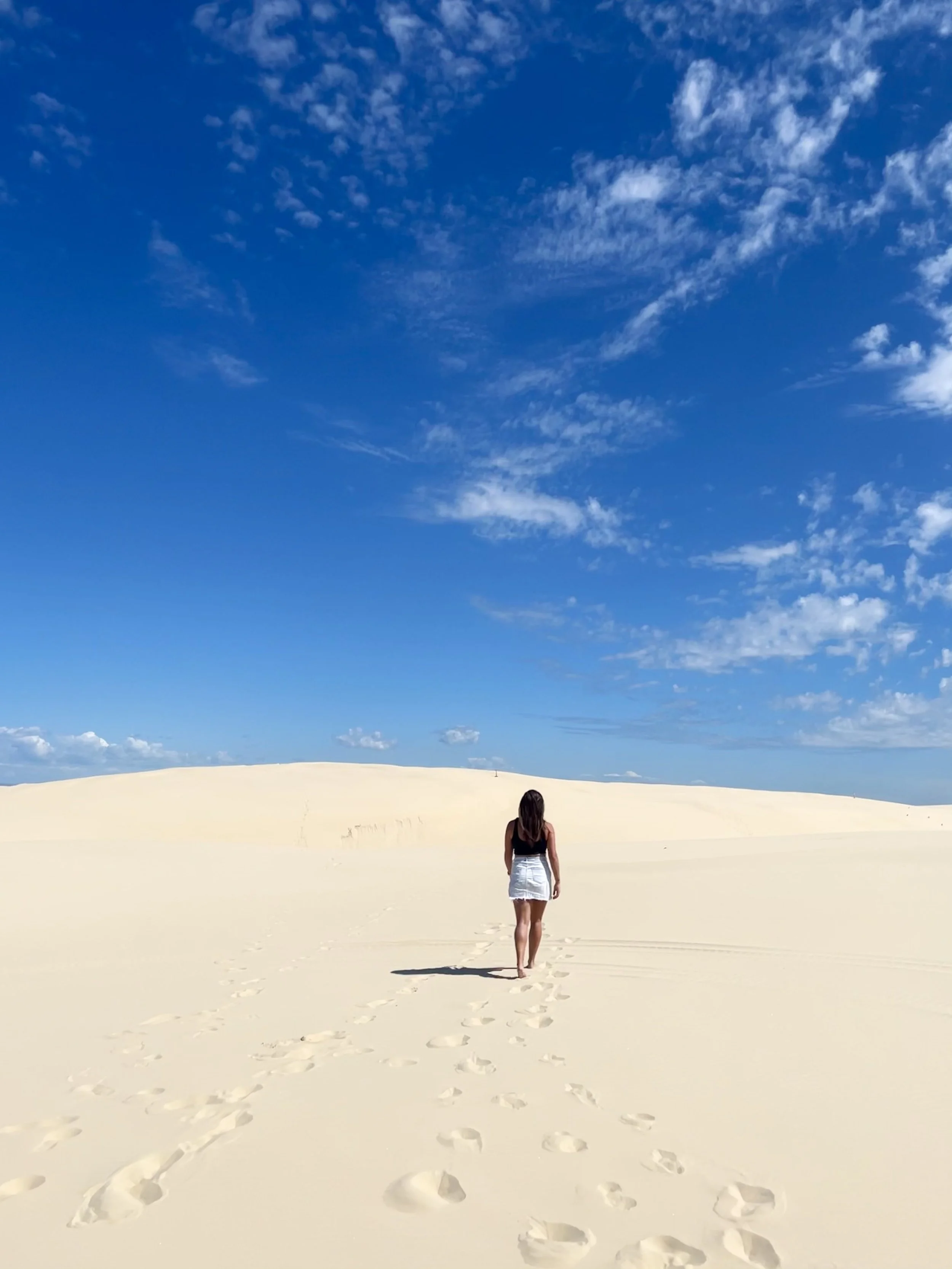 Reisvoorbereiding met een wereldkaart, een paspoort, een digitale camera, een laptop, een kopje koffie, een zonnebril en een hoed op een tafel.