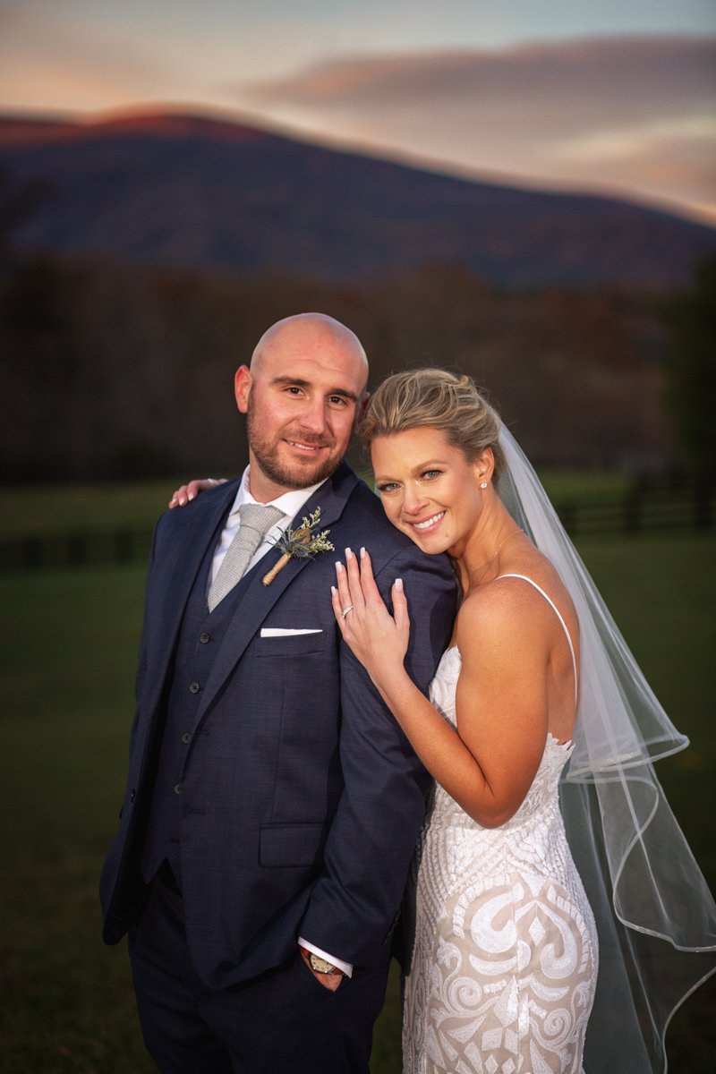 Portrait of a couple embracing, looking at the camera at sunset.