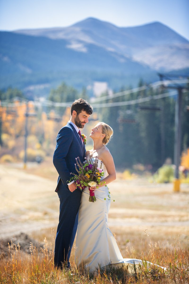 Couple stand, looking at each other in front of ski lifts at Breckenridge Resort
