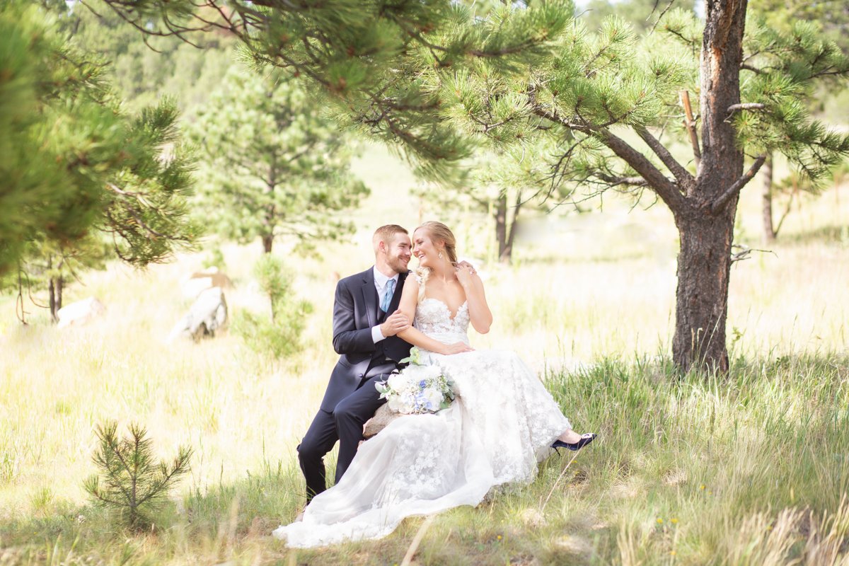 Couple sitting in a field under juniper trees.