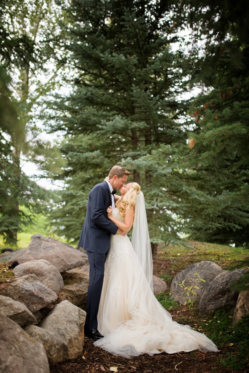 Couple embracing and kissing in a grove in the woods.
