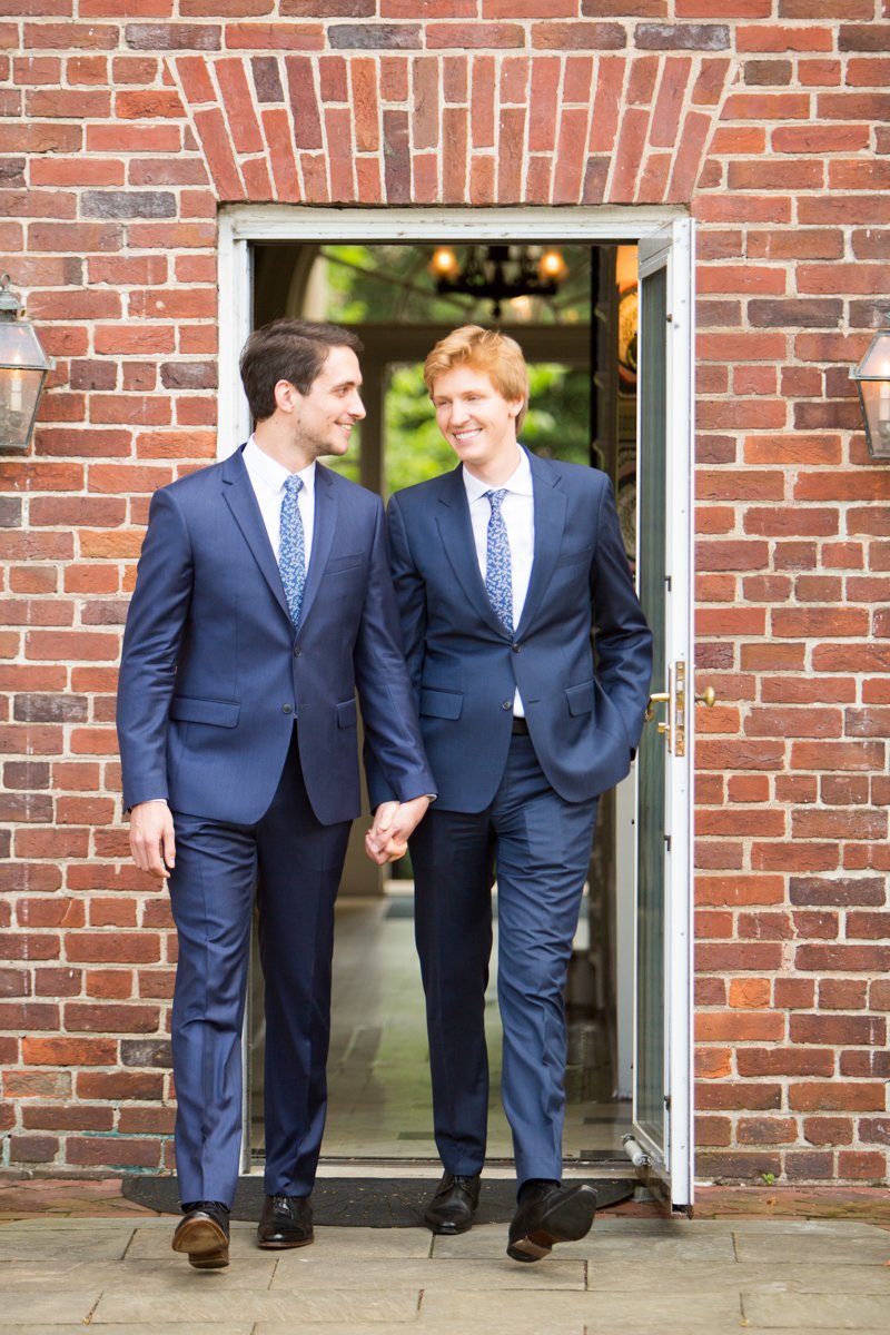 Two grooms walking through a door to their wedding ceremony