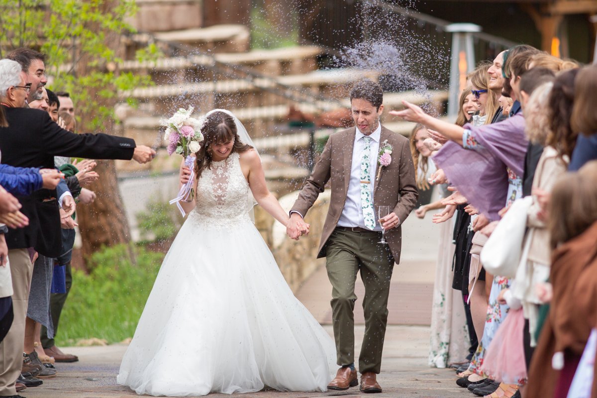 Couple walking through lavender being thrown as they exit the ceremony.