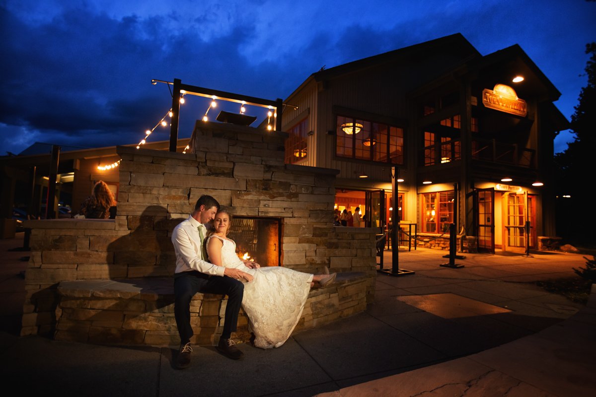 Night photo of a couple sitting by the fire in front of the Silverthorne Pavilion. The venue is illuminated behind them.