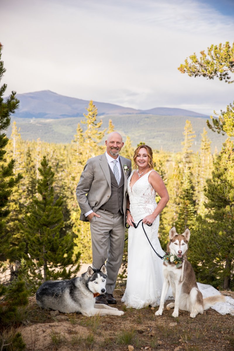 Couple with their two husky dogs in the mountains at sunset.