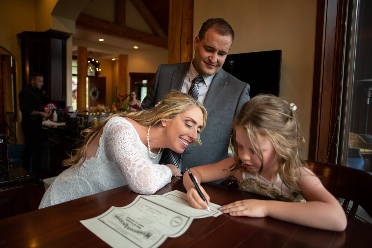 Couple watch as their daughter signs their marriage certificate as an official witness.