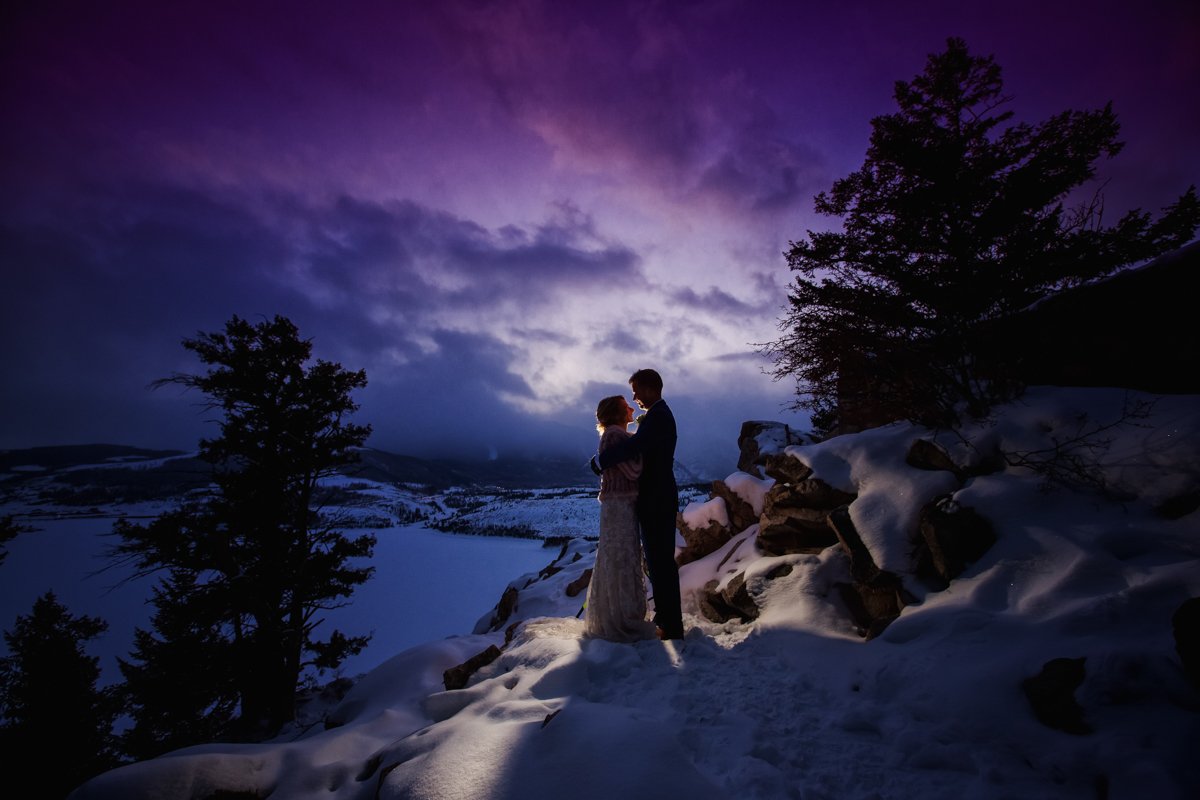 late sunset shot. Blue and purple hues in the sky. Couple silhouetted with a light behind them. on a cliffside.